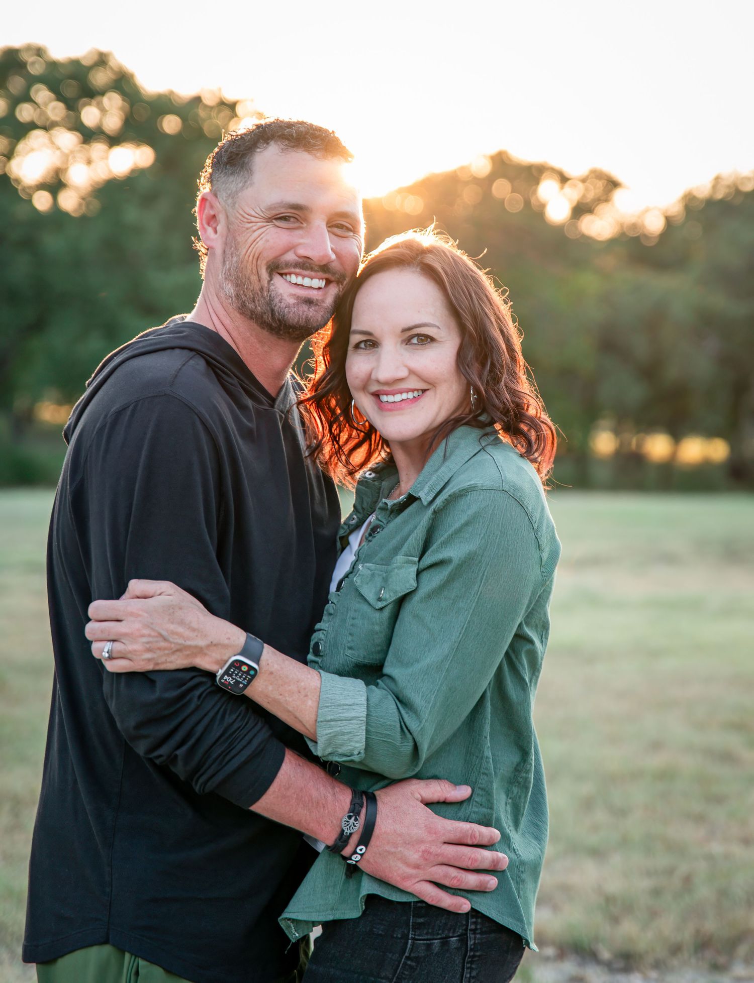 Romantic sunset portrait of a couple embracing outdoors in casual fall clothing.
