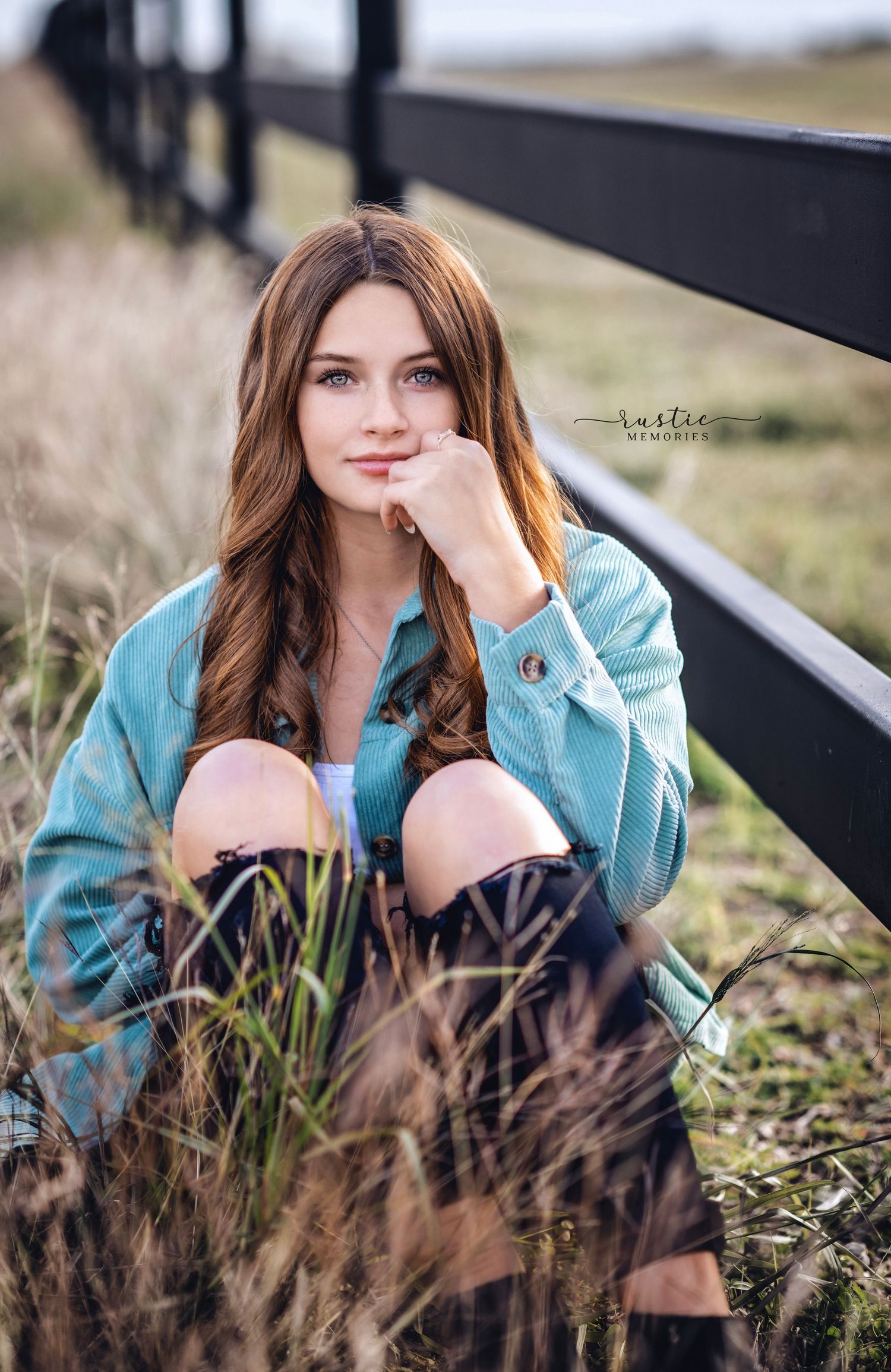 Portrait session in field featuring person in turquoise jacket amid tall grass.