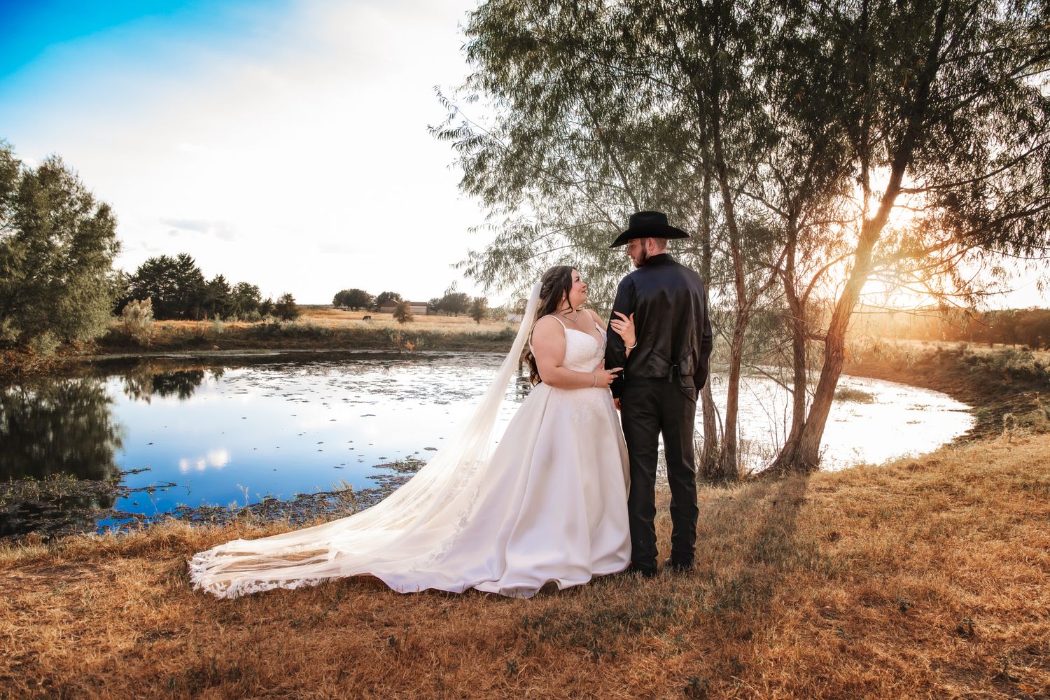 Romantic waterfront sunset photos of a wedding couple against a golden sky.