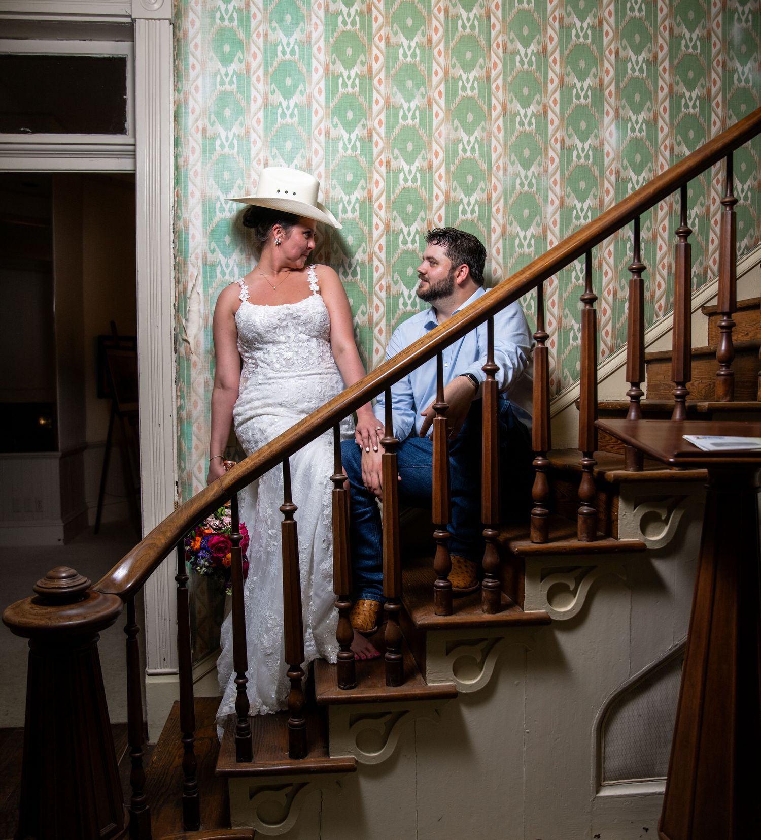 Wedding scene in vintage setting with green wallpaper and wooden staircase.