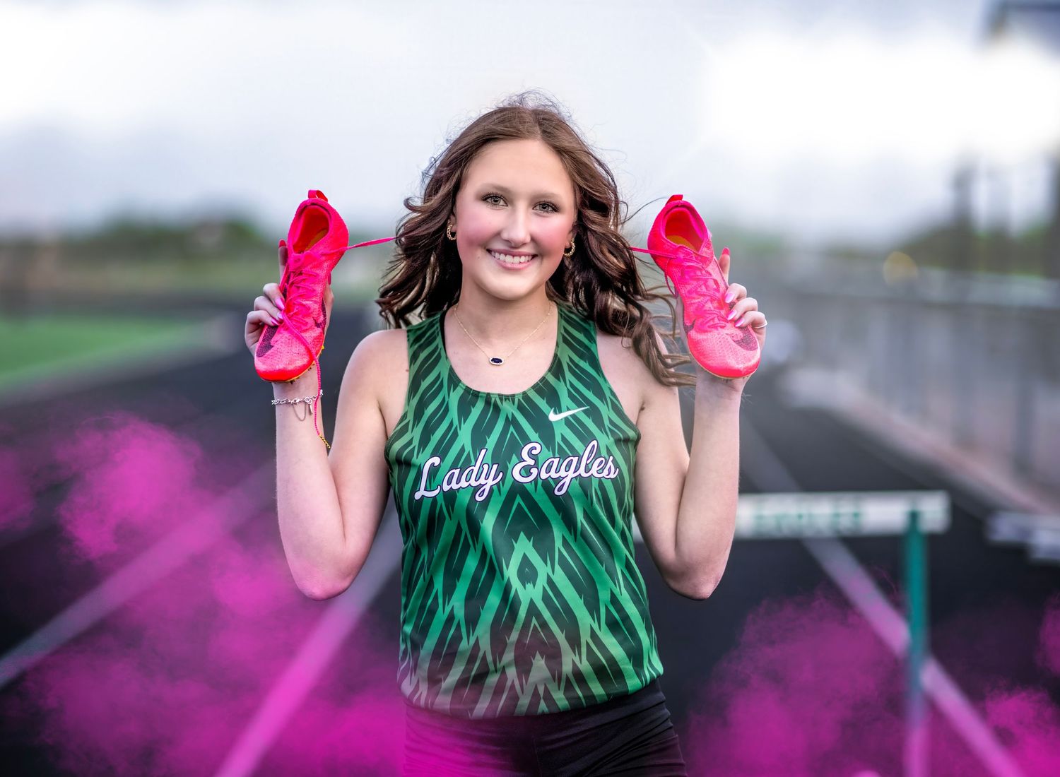 Athletic shots on track with bright pink smoke effects and green uniform.