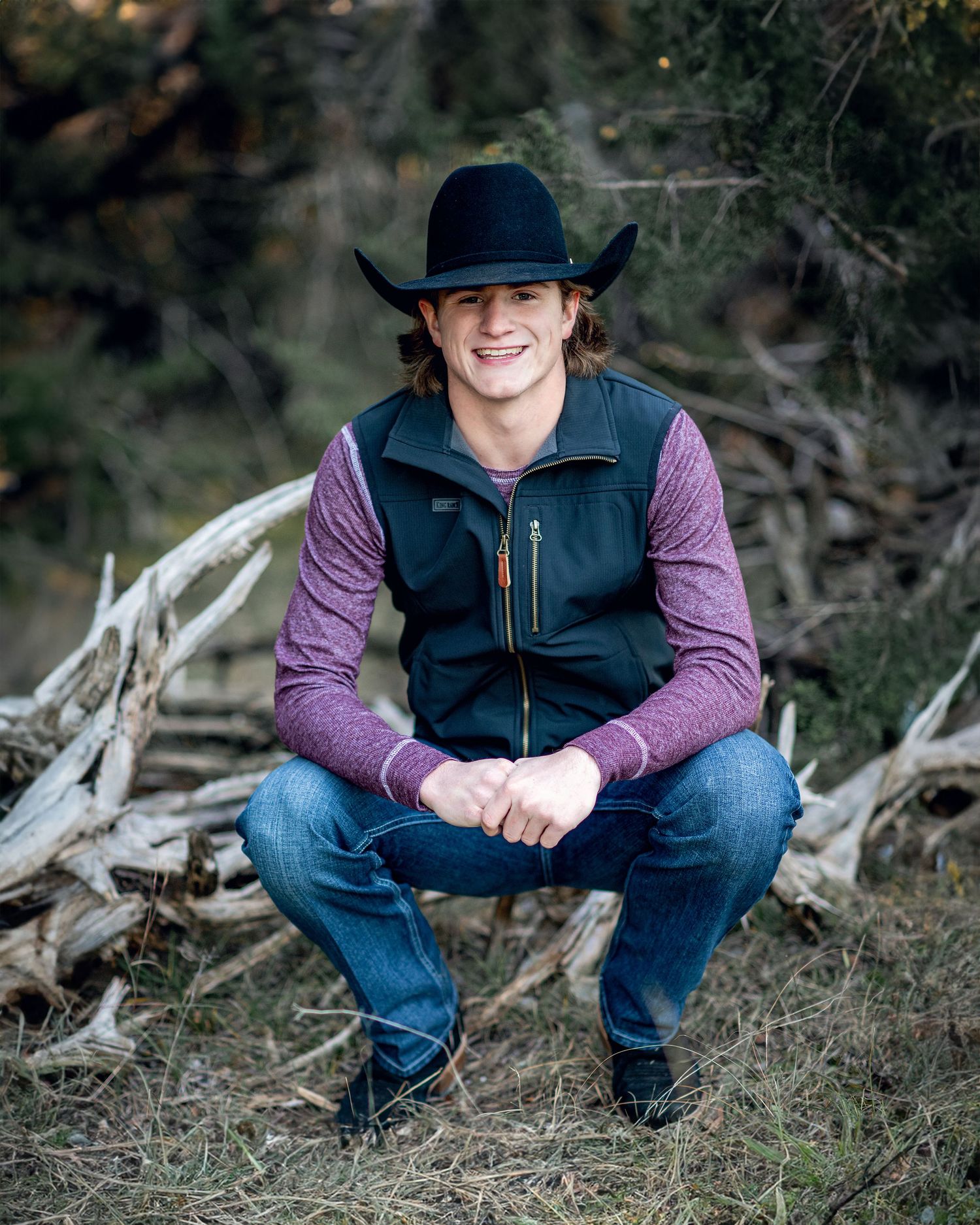 Person wearing cowboy hat and vest poses outdoors in casual western attire.
