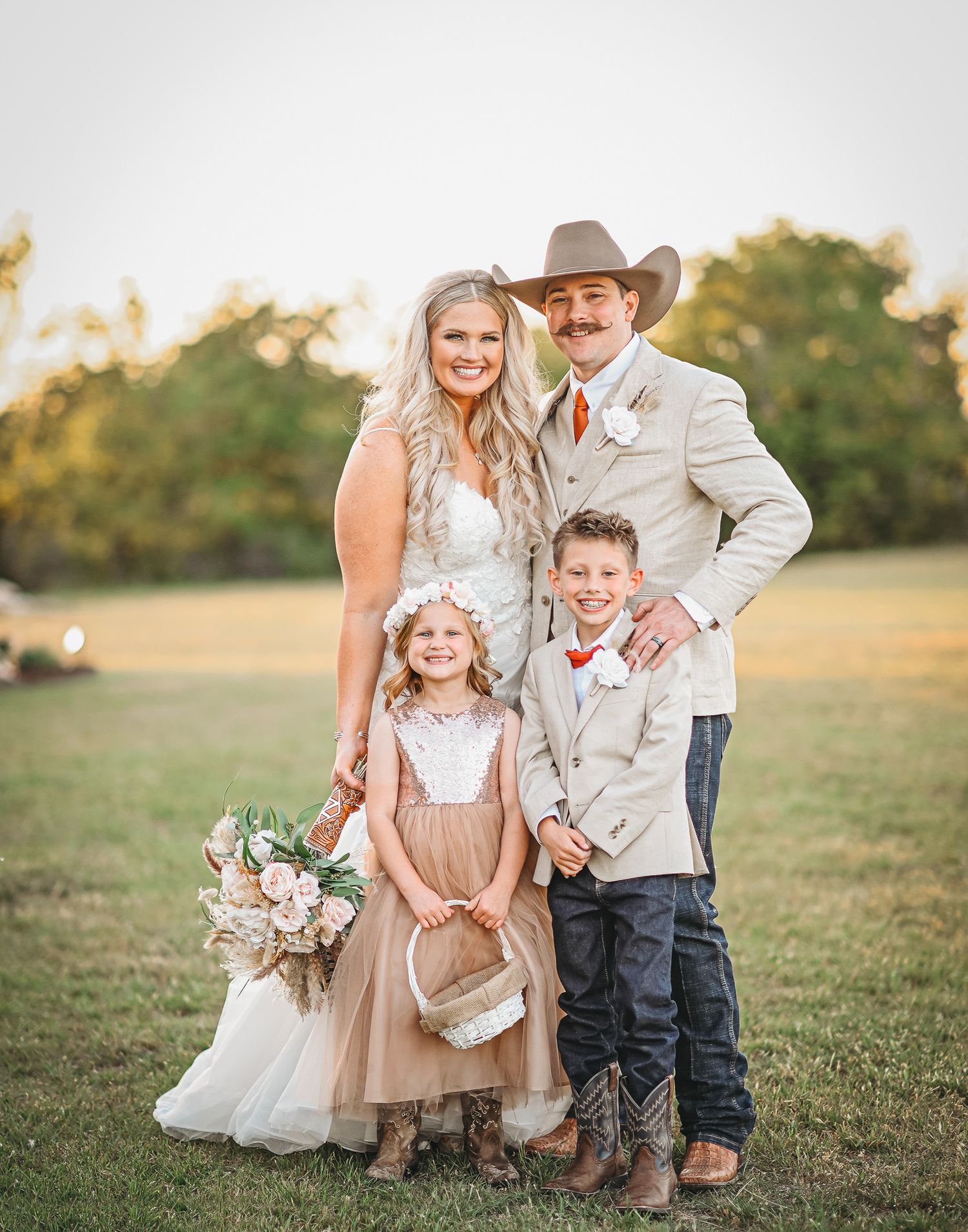 A rustic country wedding portrait with children in a sunset field.