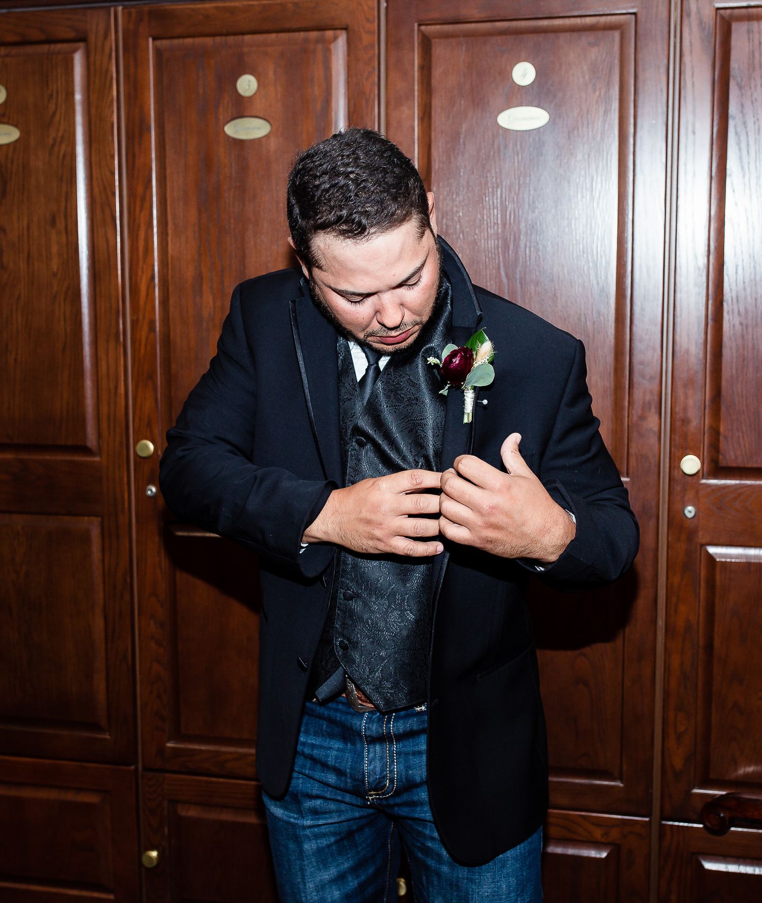 Wedding preparation moment in formal attire against wood paneled wall.