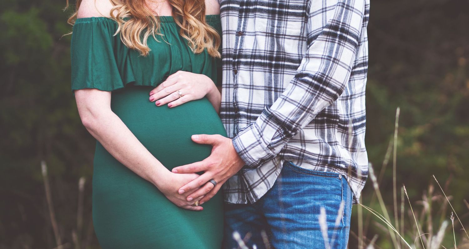 Intimate maternity portraits in nature with couple in matching casual outfits.