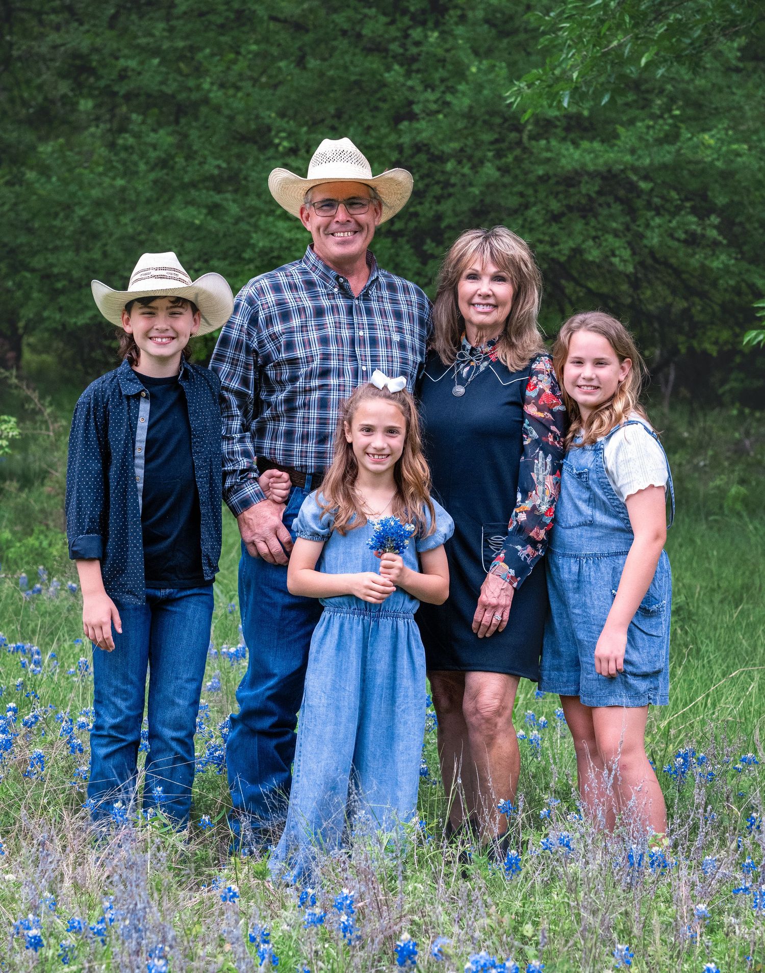 Family portrait in a wildflower meadow with cowboy hats and western attire.