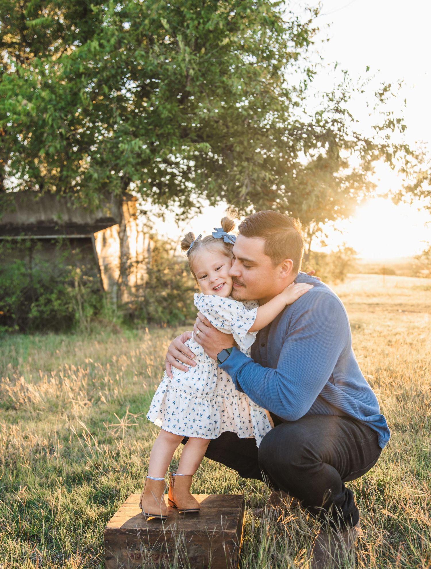 A touching moment between parent and child on a wooden crate during golden hour.