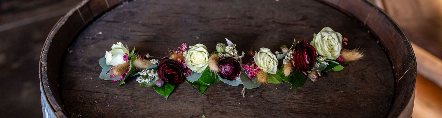 Row of delicate floral boutonnieres arranged on wooden surface.