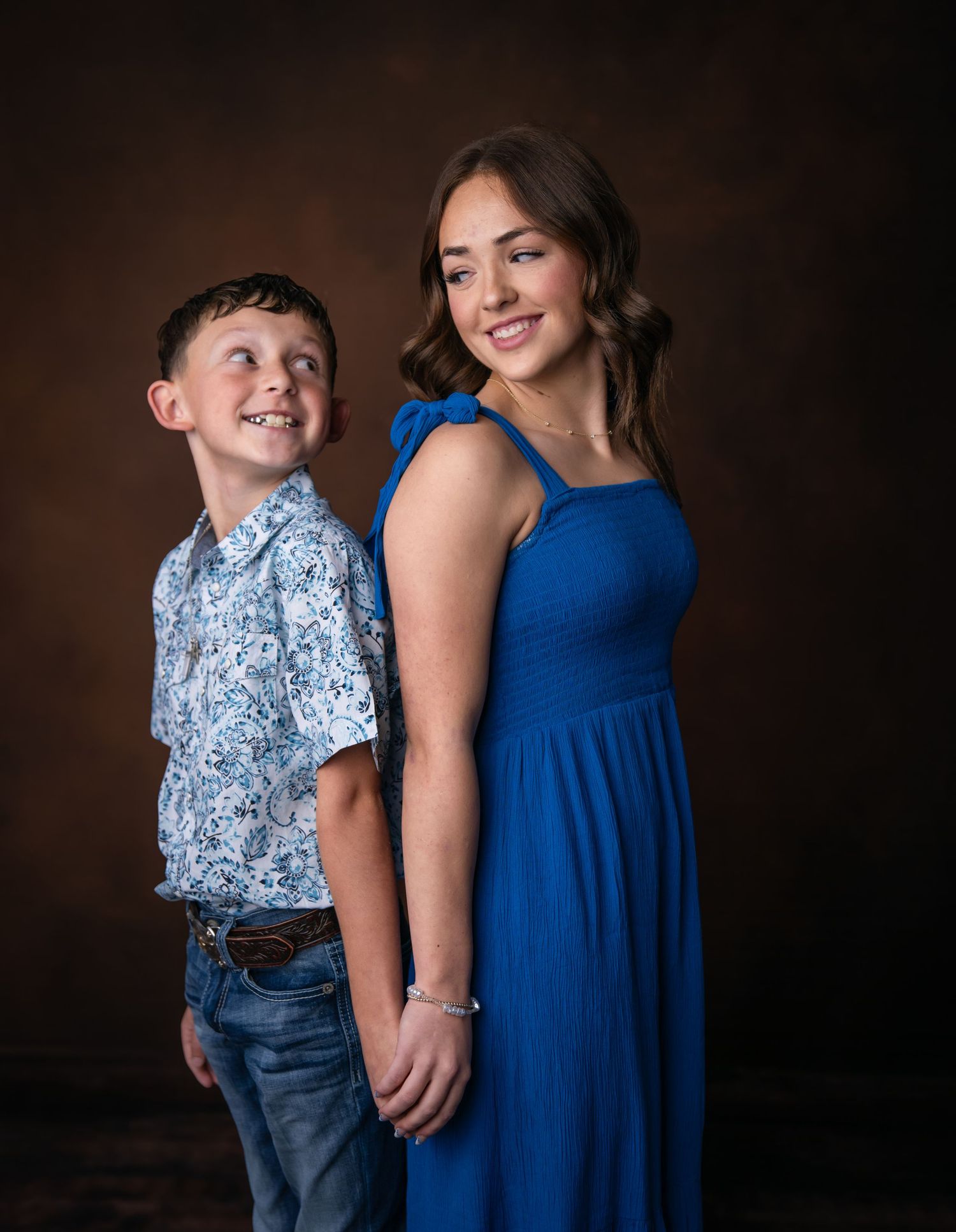A series of four similar studio portraits showing a young child and adult in blue outfits against a dark background.