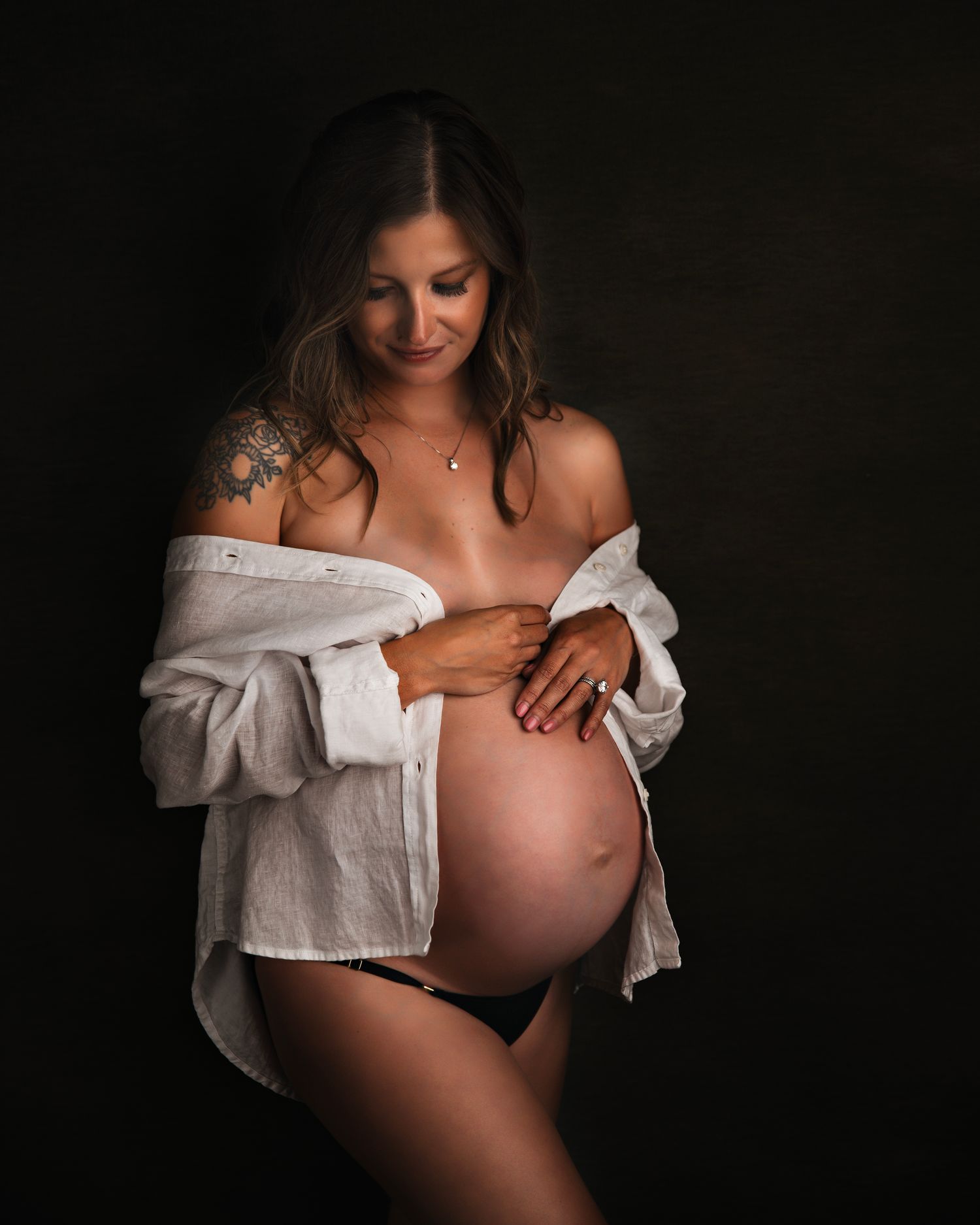 Artistic maternity photoshoot series in black and white with white fabric against dark background.