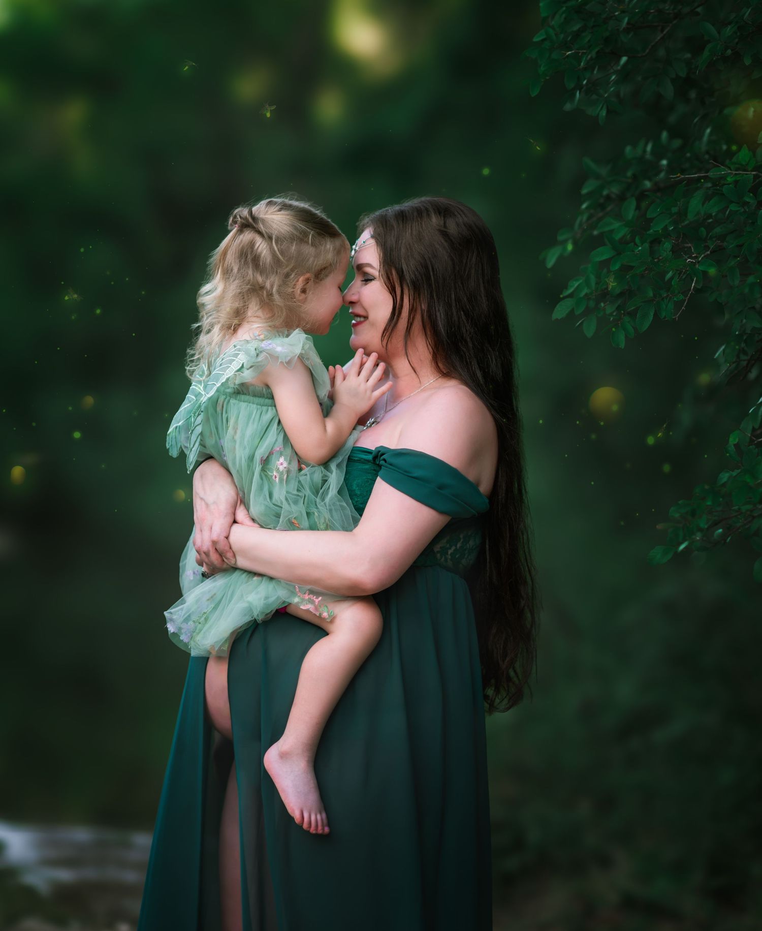 Tender moment captured in forest setting with emerald matching dresses.