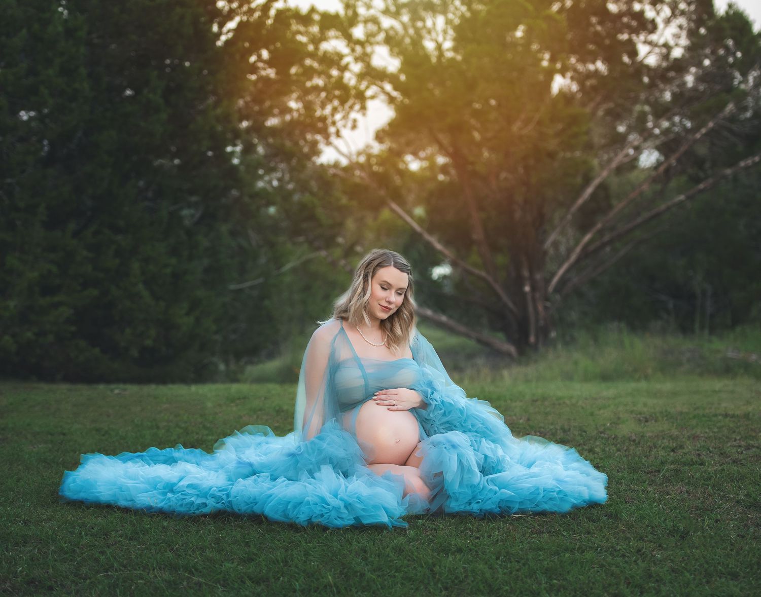 Dreamy maternity photos with woman in flowing blue gown at golden hour.