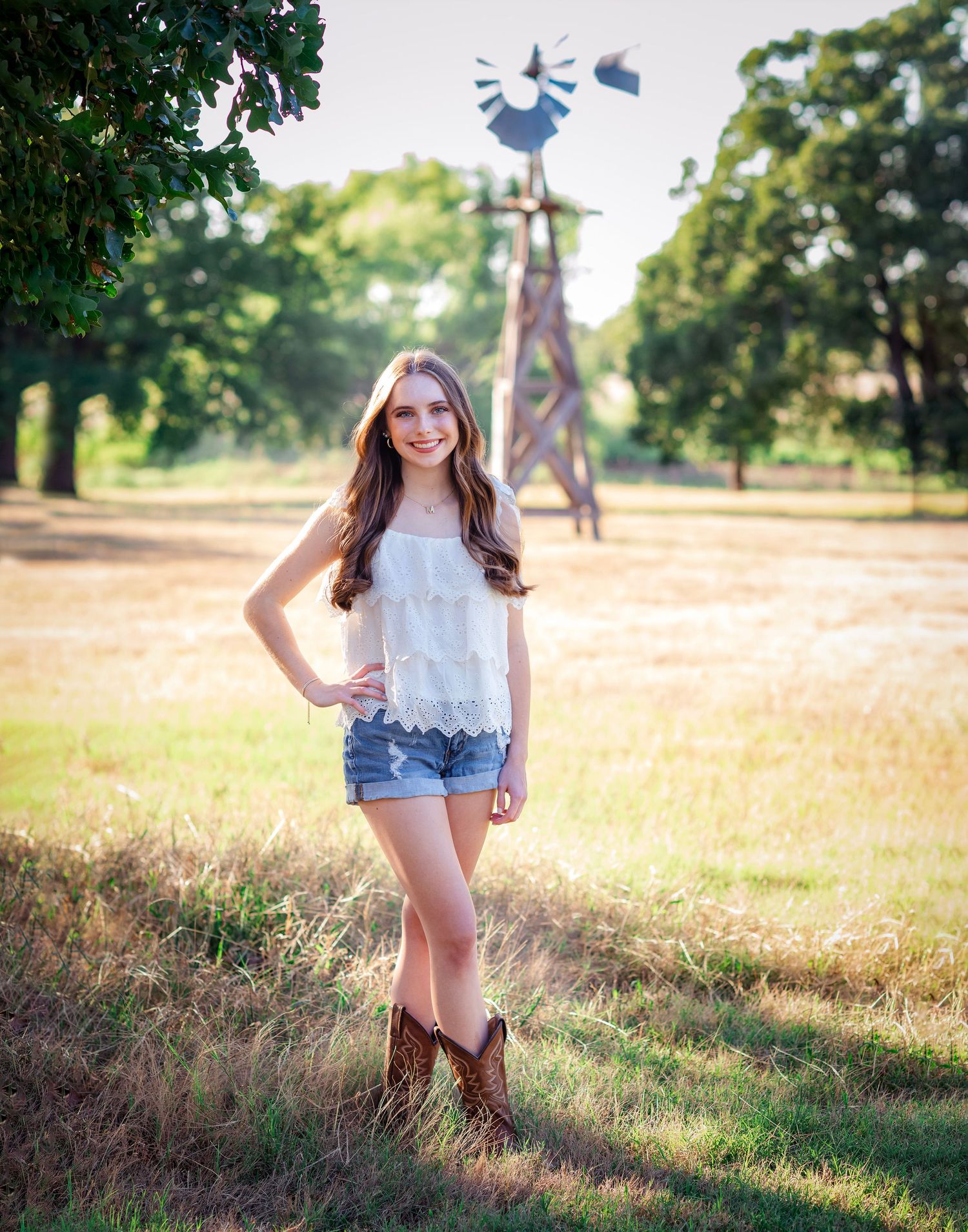 Country style portrait with rustic windmill in background during golden hour.