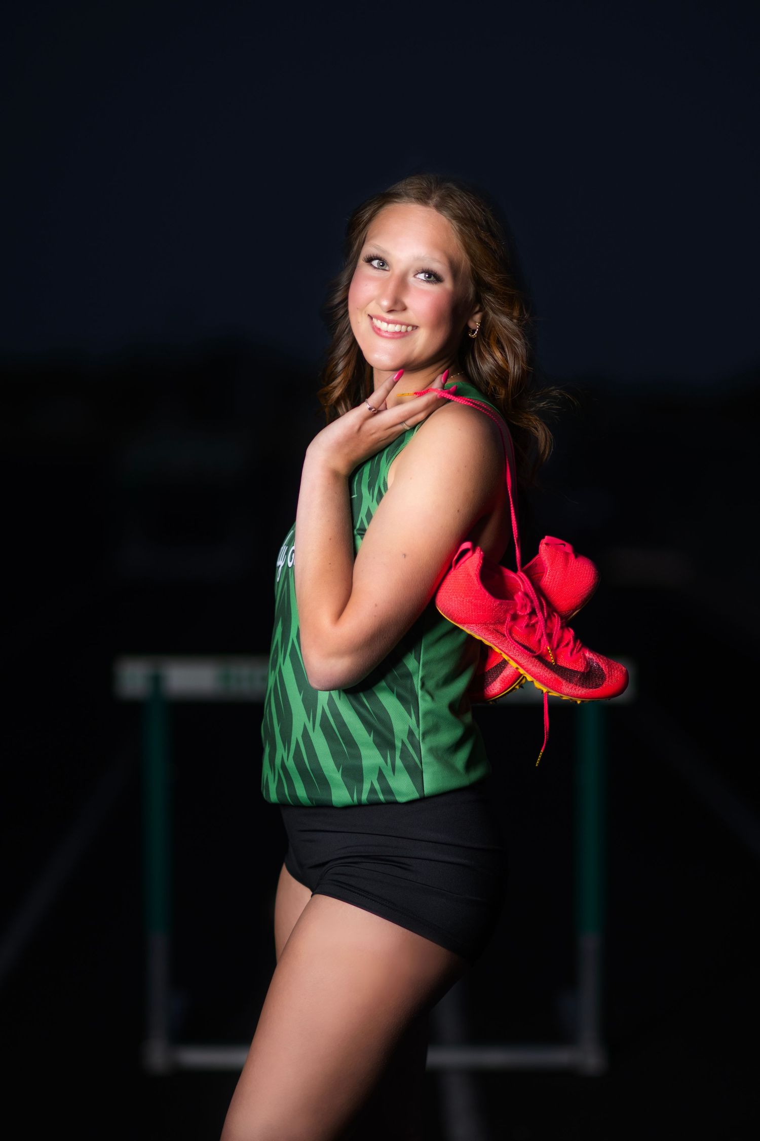 Dramatic nighttime athletic portraits featuring green uniform and bright pink props.