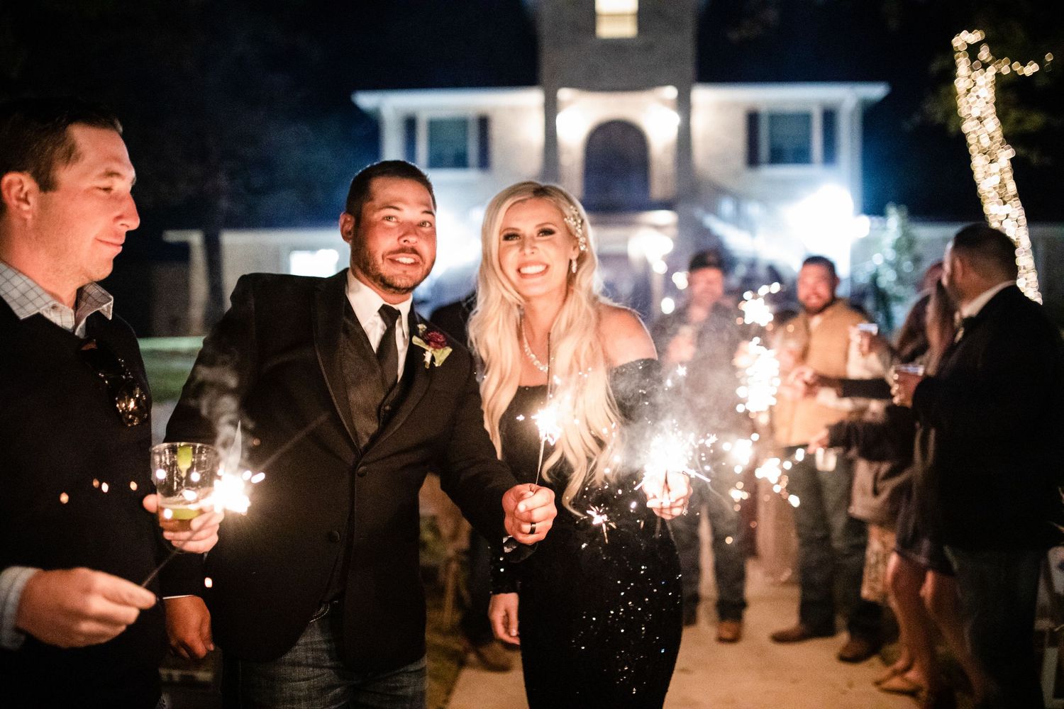 A sparkler exit celebration at night outside an elegant white house.