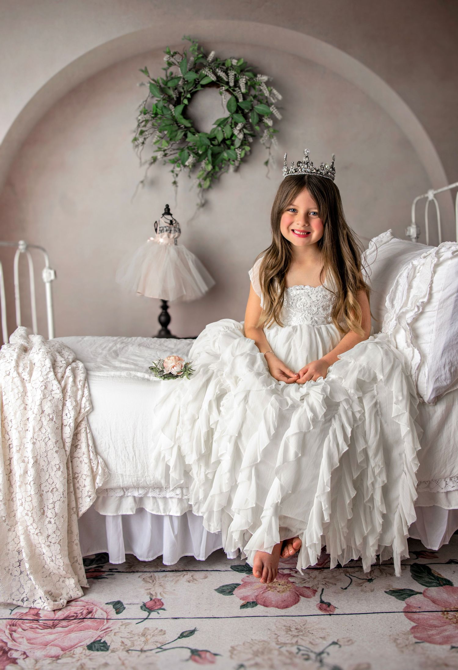 Whimsical portrait session with white vintage dresses displayed along arched wall.