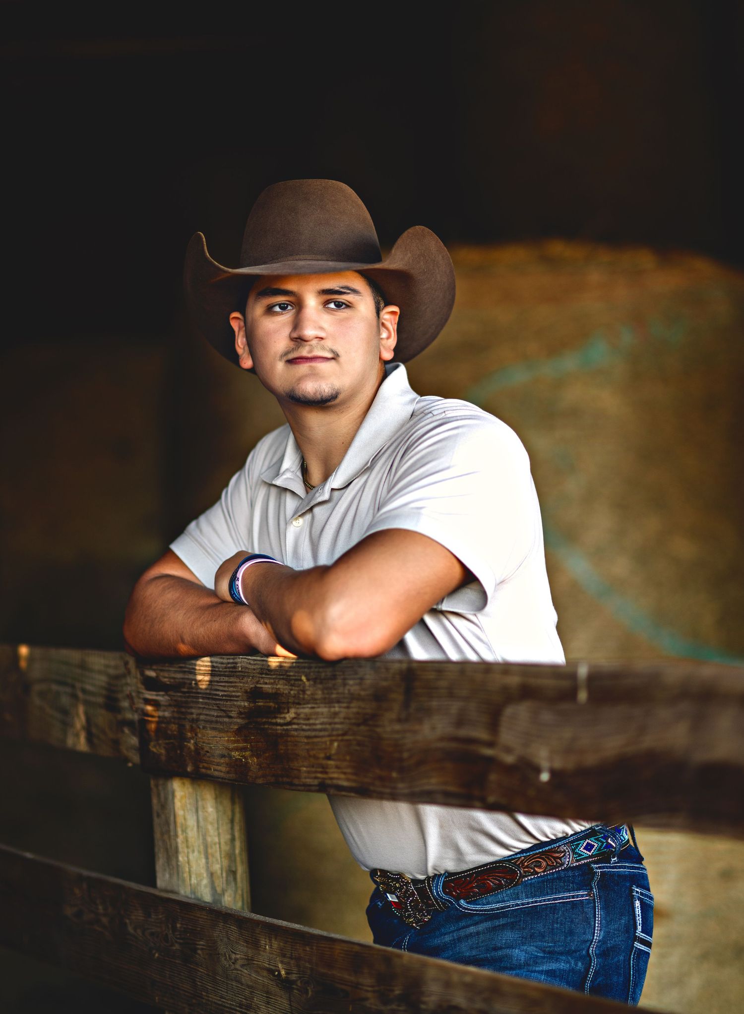 Rustic western-themed portrait series featuring casual poses along wooden fence.