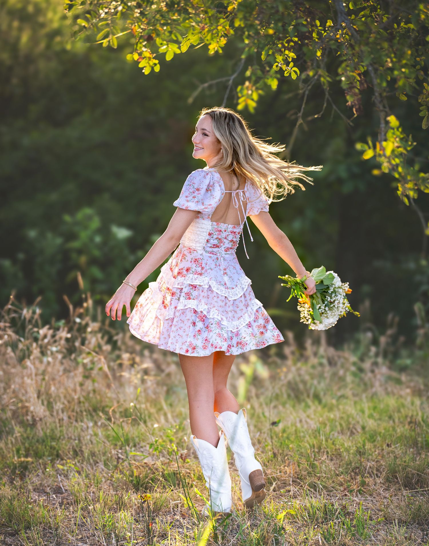 A young girl in a floral dress and white boots twirls playfully in a sun-dappled meadow on a warm autumn day.