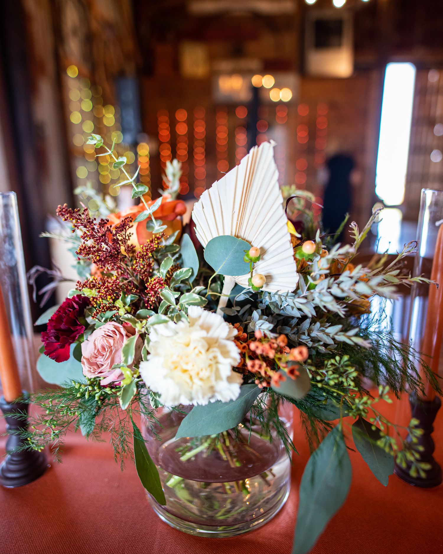 Romantic floral arrangement with pink roses and mixed flowers in glass vase on dark table.