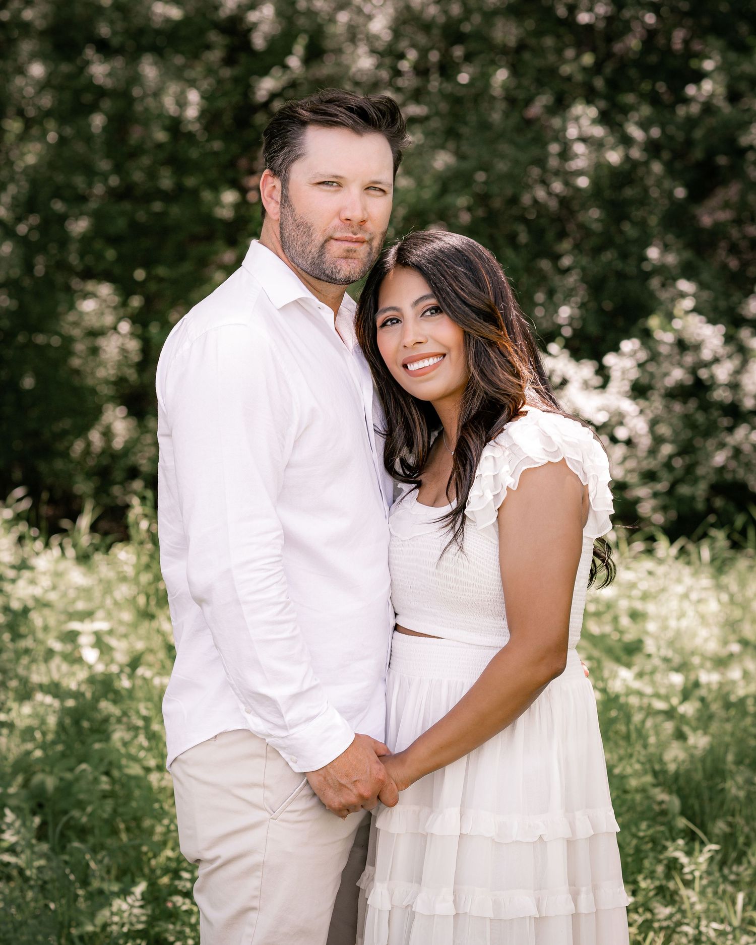 Romantic couple portraits in white outfits among blooming spring flowers.
