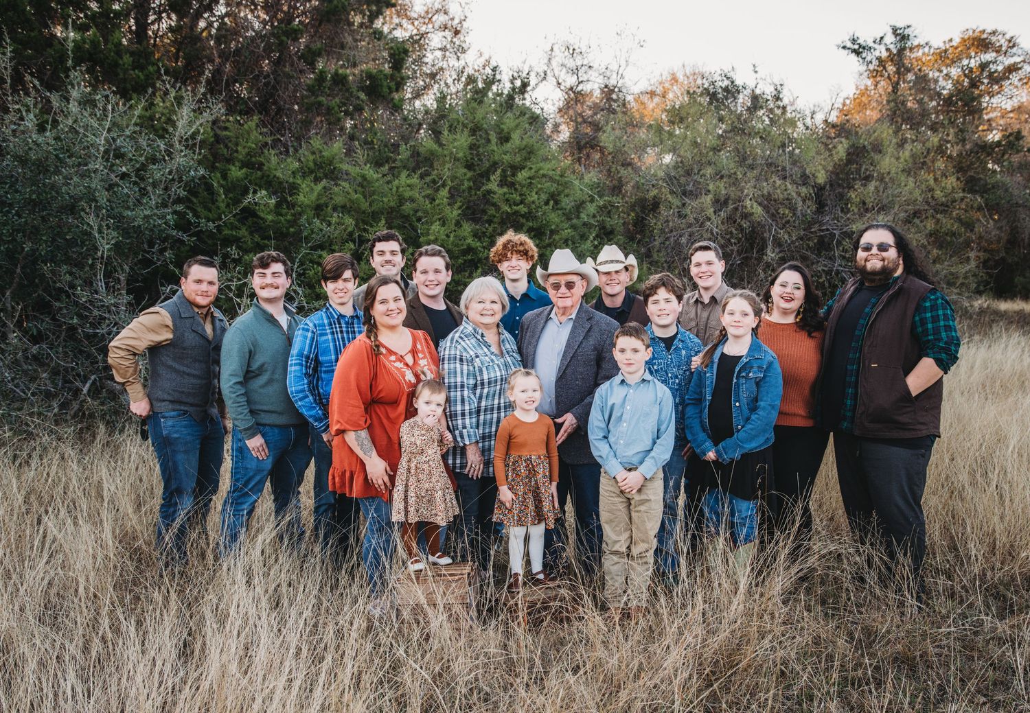 Extended group portrait in a rustic field with tall grass during autumn.