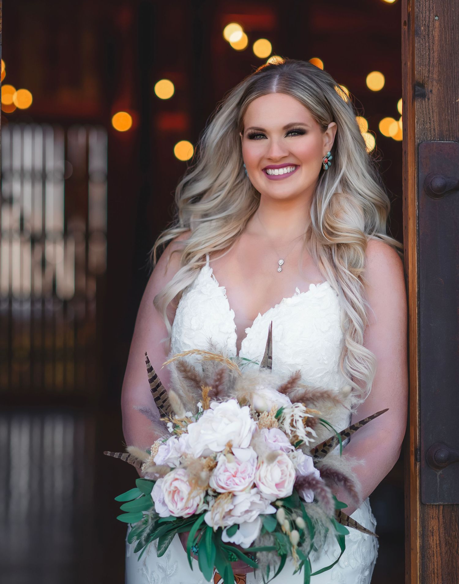 Elegant bridal portrait with blush and cream bouquet against rustic wooden backdrop.