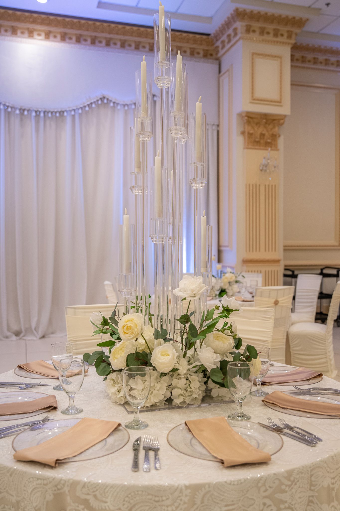 Elegant wedding table setting with tall glass candelabra and white rose centerpiece.