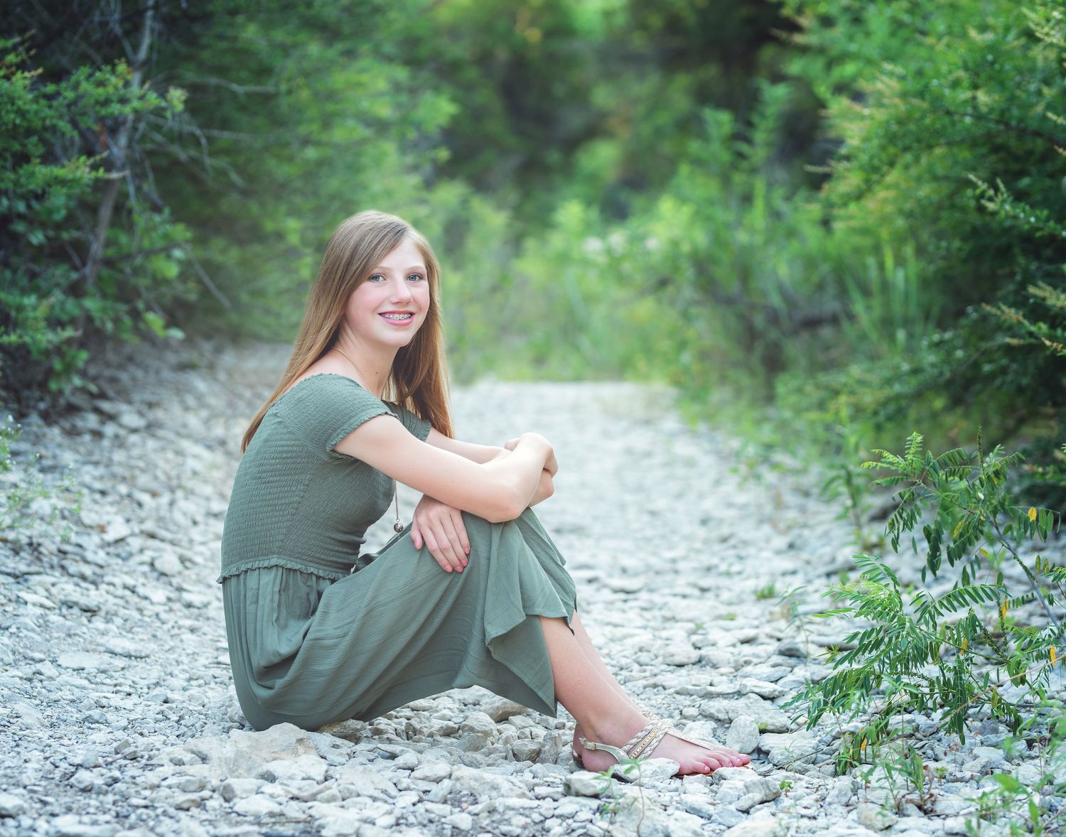 Relaxed outdoor photoshoot on rocky path surrounded by lush green foliage.