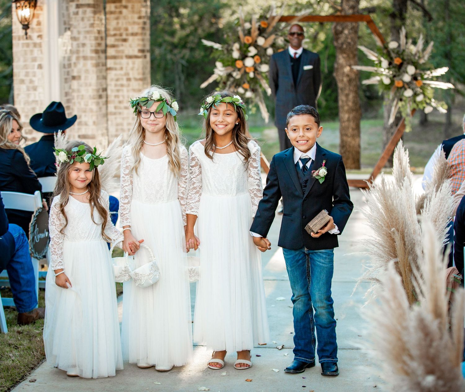 Wedding party of children in white dresses and formal attire pose together.