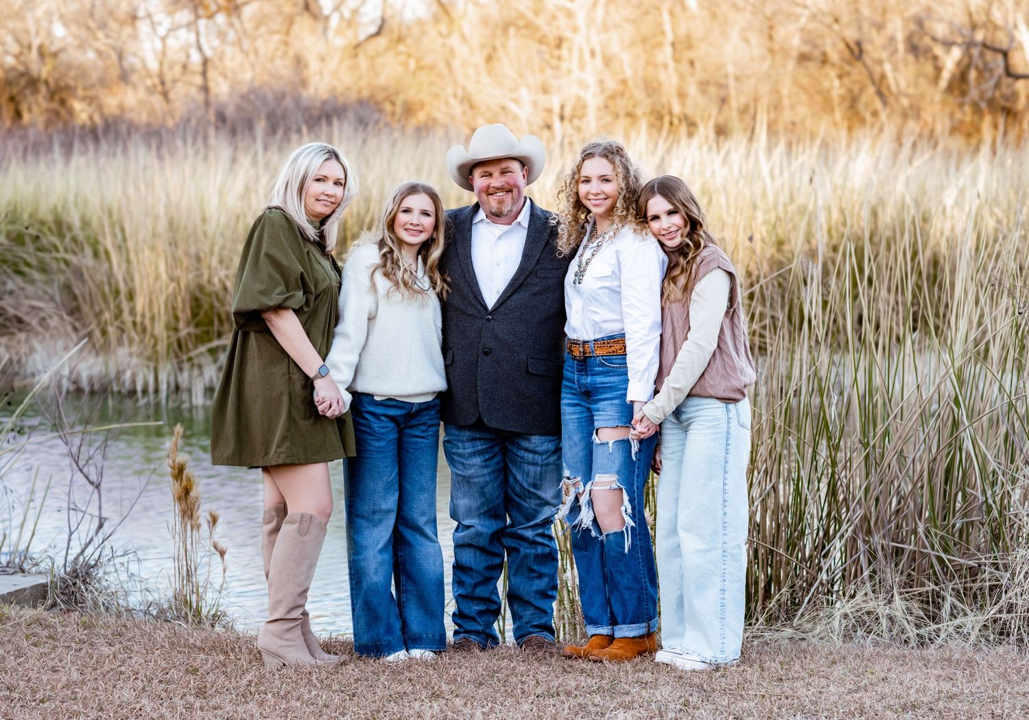 Family group photos taken in golden field during sunset with rustic casual attire.