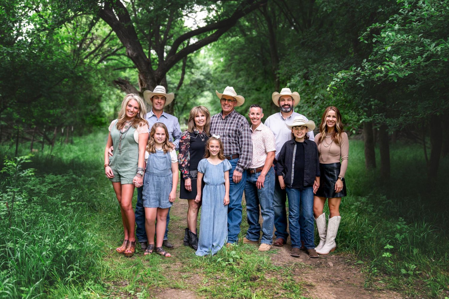 Group photo on a forest path surrounded by lush green trees in casual summer attire.