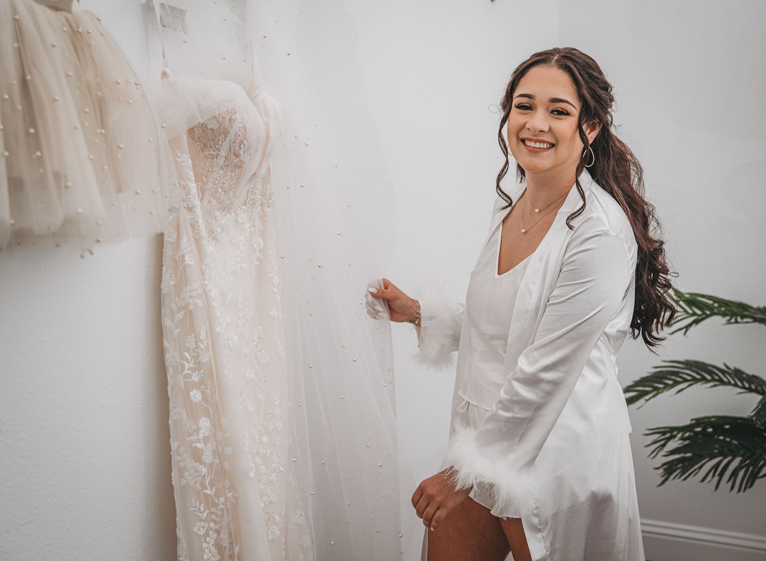 A pre-wedding moment in a bridal boutique with a white lace gown hanging on display.