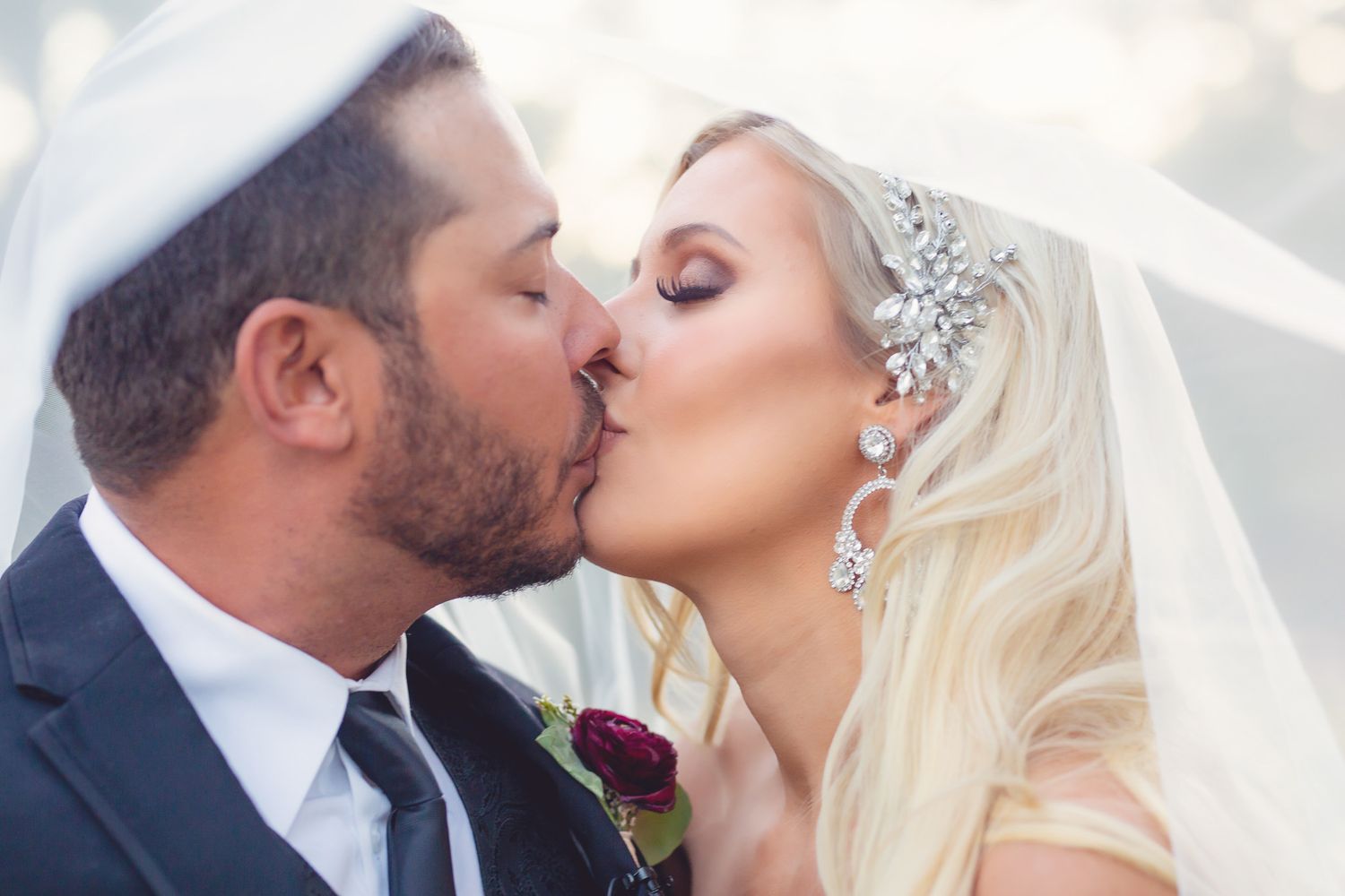 Intimate wedding moment captured under a flowing white veil.