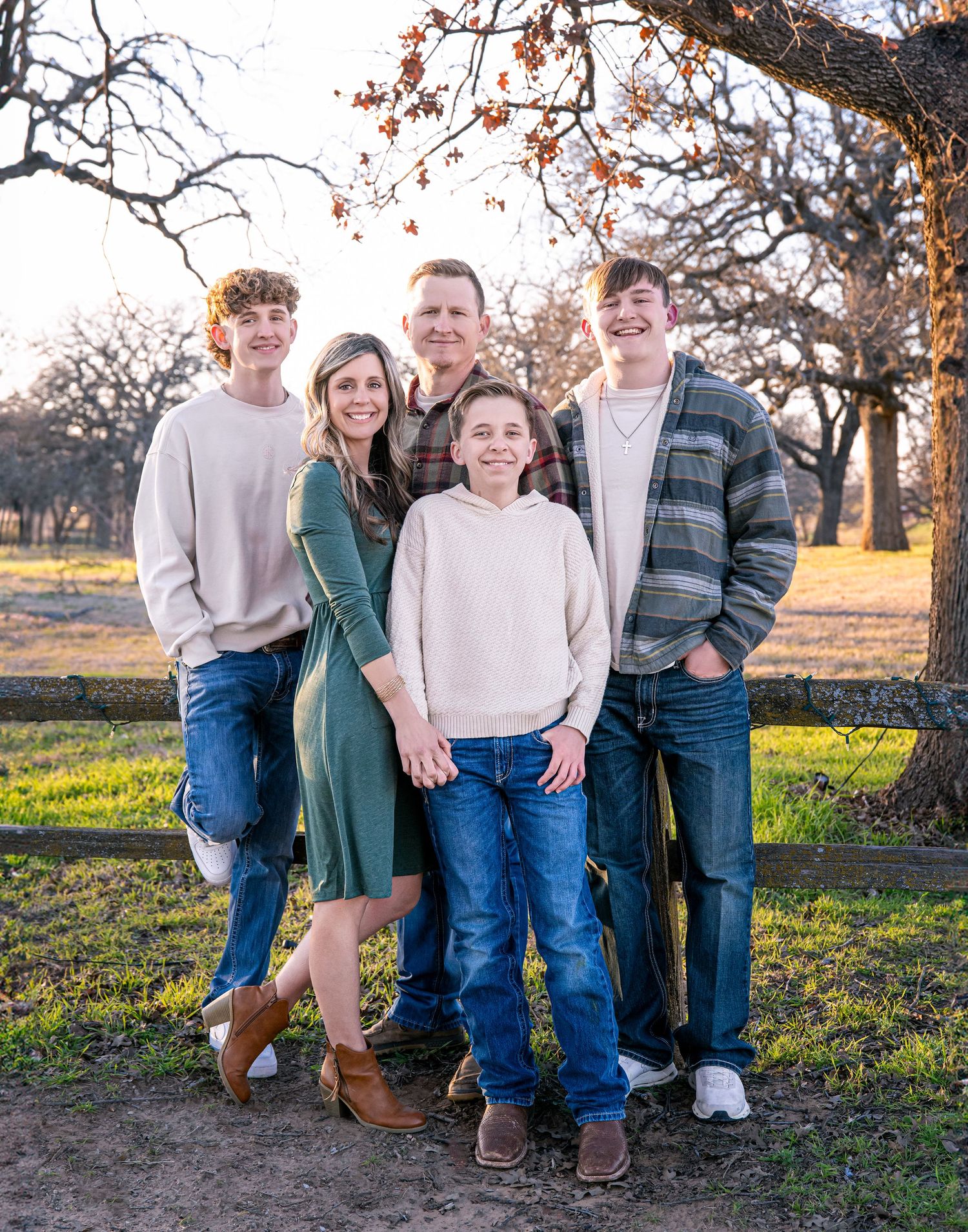 Extended family poses together under oak trees during golden hour portrait session.