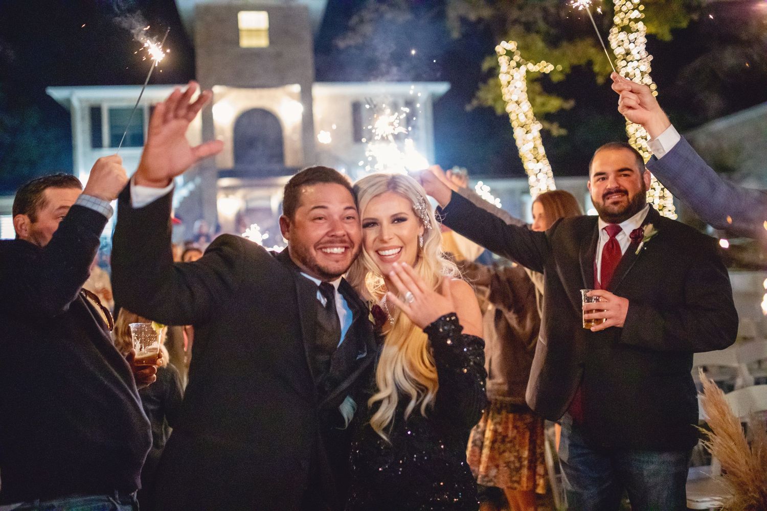 Wedding celebration with guests and couple dancing under nighttime lighting.