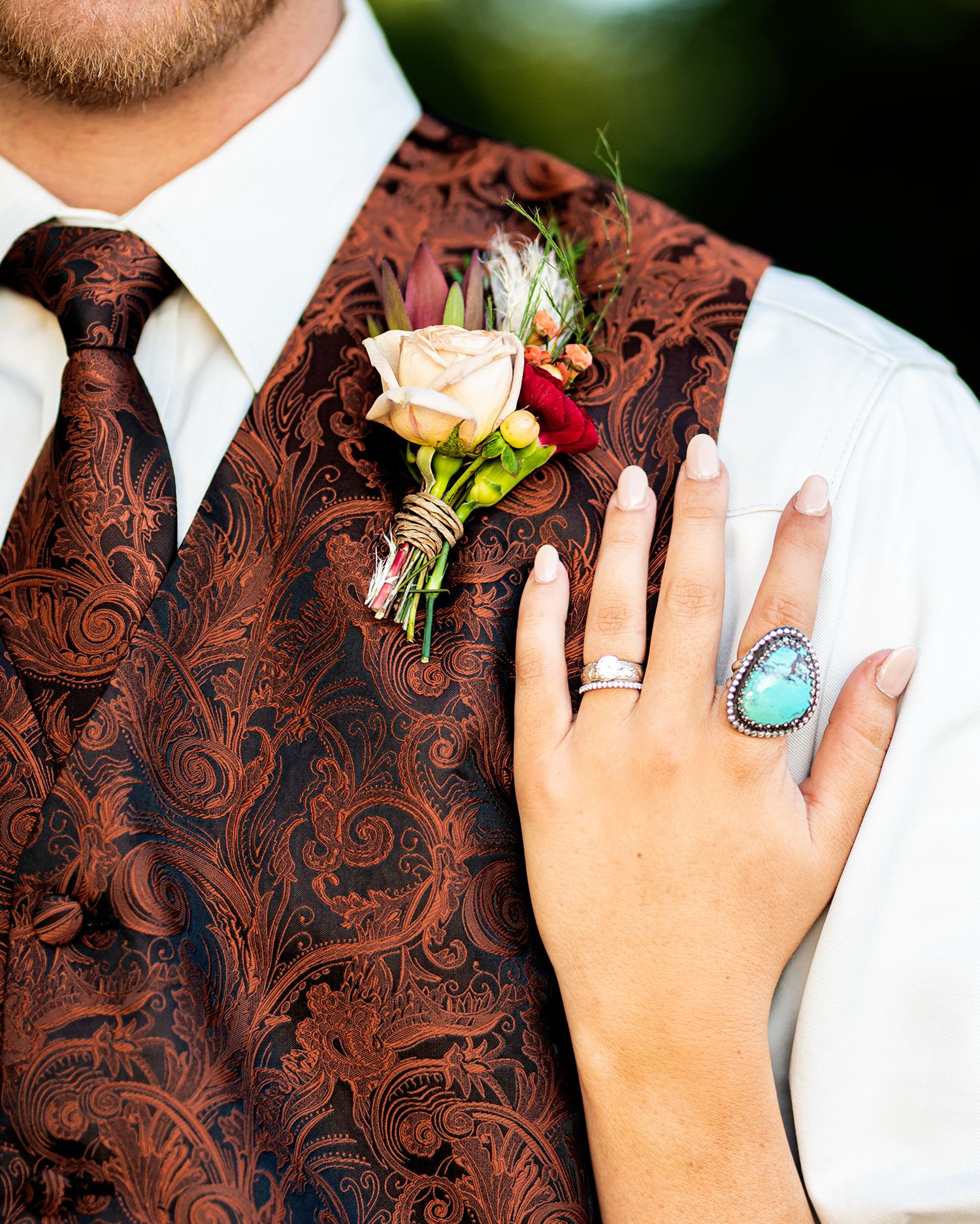 Brown paisley vest with rose boutonniere and turquoise ring detail.