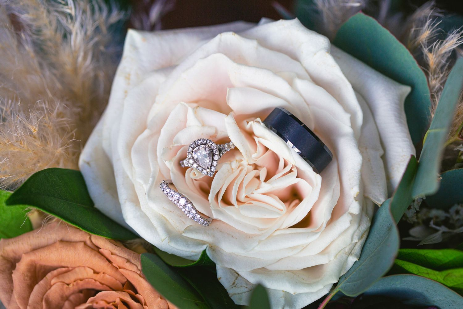 Elegant peach and white roses with green foliage arranged as wedding decor on a rustic surface.