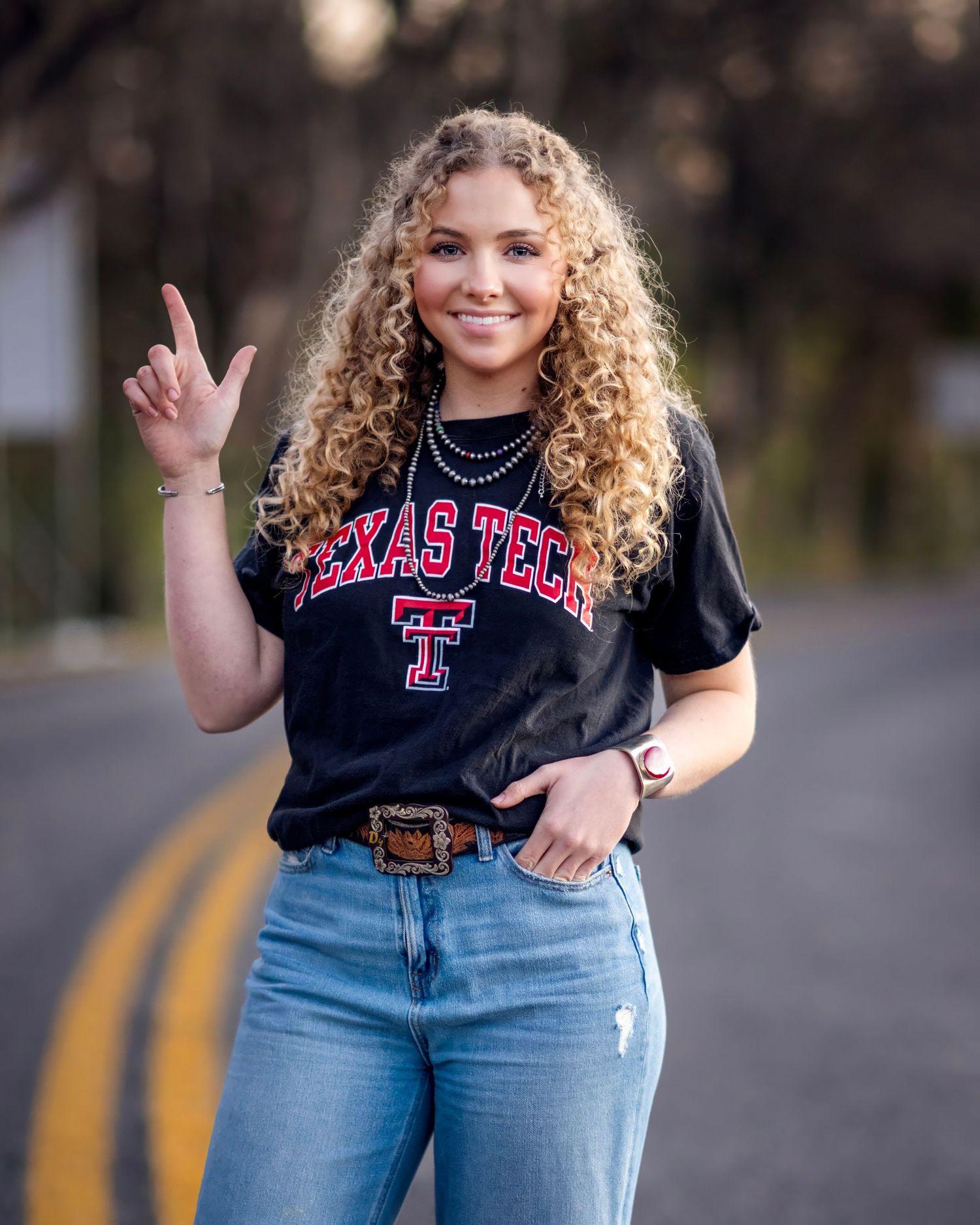 Student wearing Texas Tech shirt poses casually on rural road.