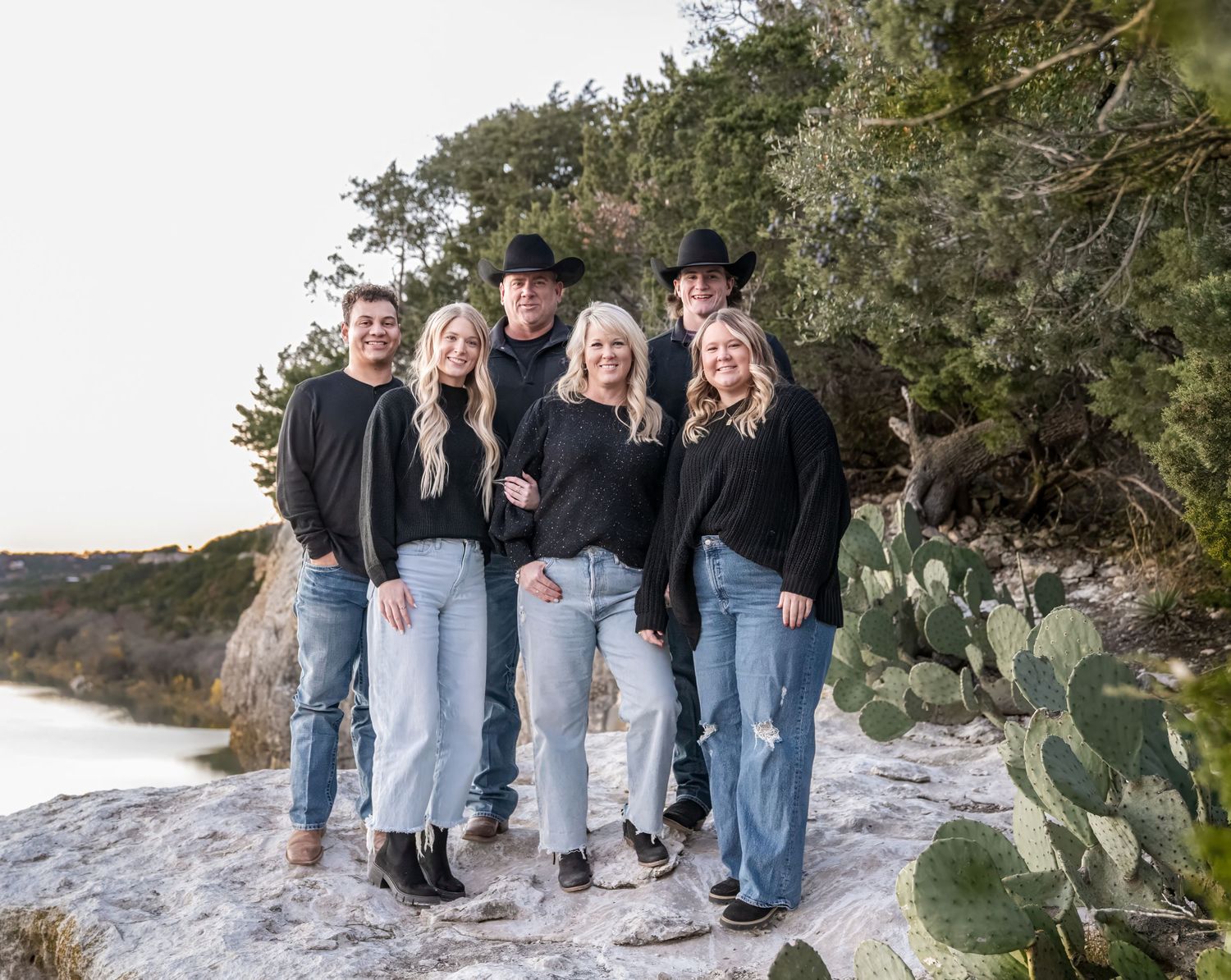 Group photo taken outdoors near cacti and coastal rocks wearing matching black tops and blue jeans.