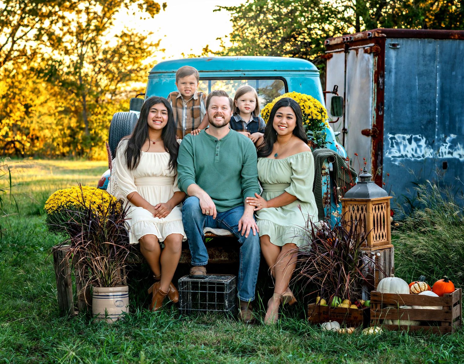 Group seated on vintage blue truck tailgate with fall decorations and props.