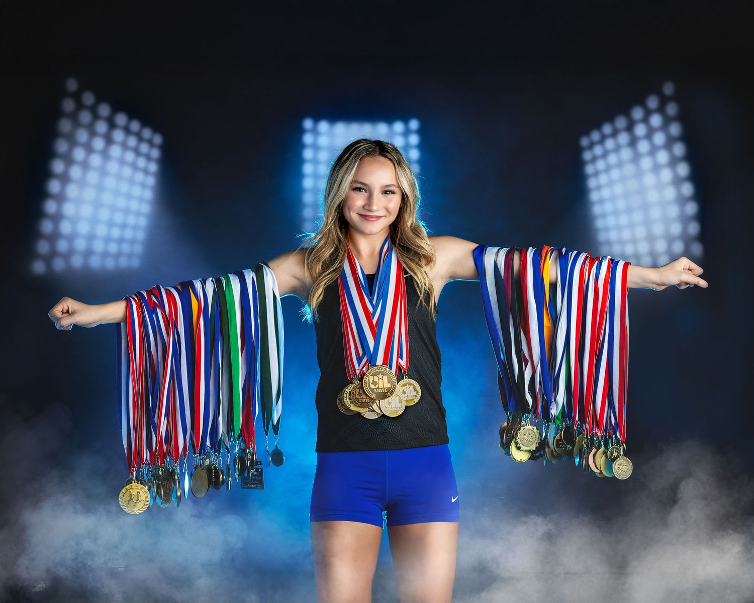 Athlete in blue uniform displays collection of medals and ribbons against dramatic blue backdrop with fog effects.