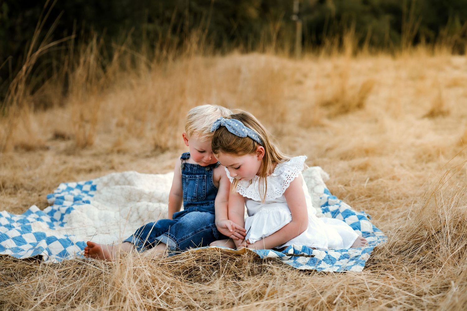 Candid moment captured of people relaxing on a picnic blanket in dry grass field.
