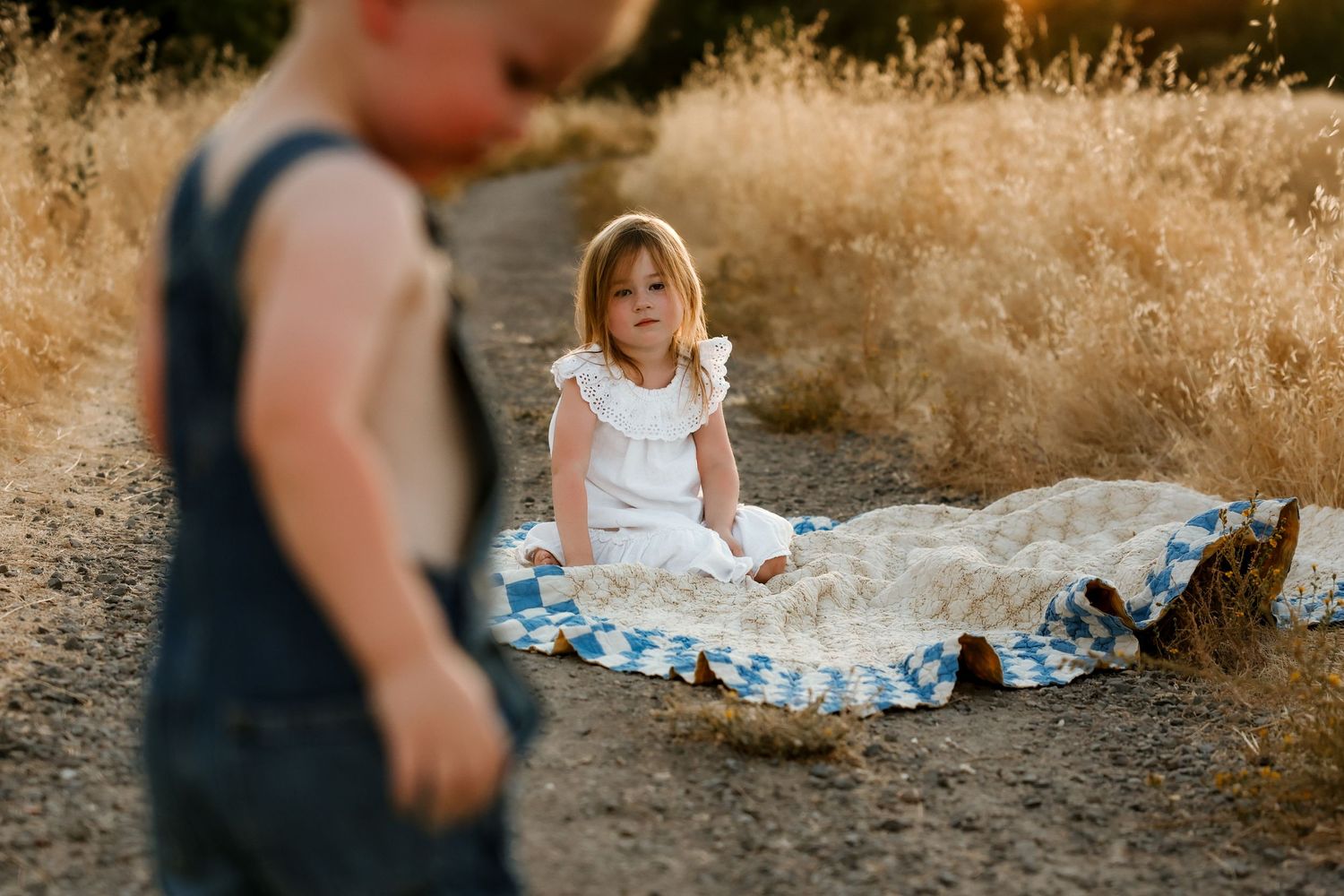Family enjoying a casual outdoor picnic on checkered blanket at golden hour.