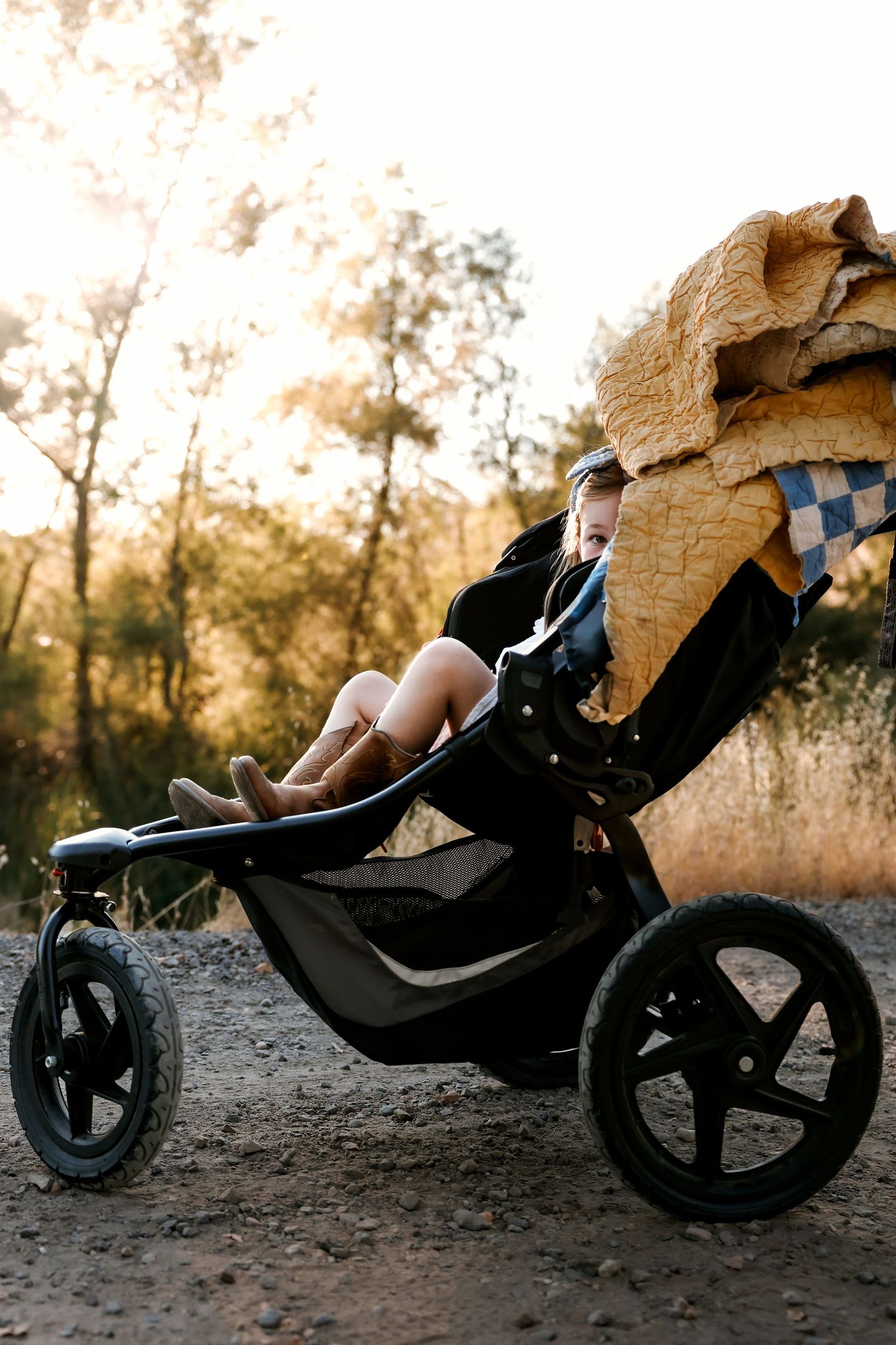 A black jogging stroller sits on a dirt path during sunset.