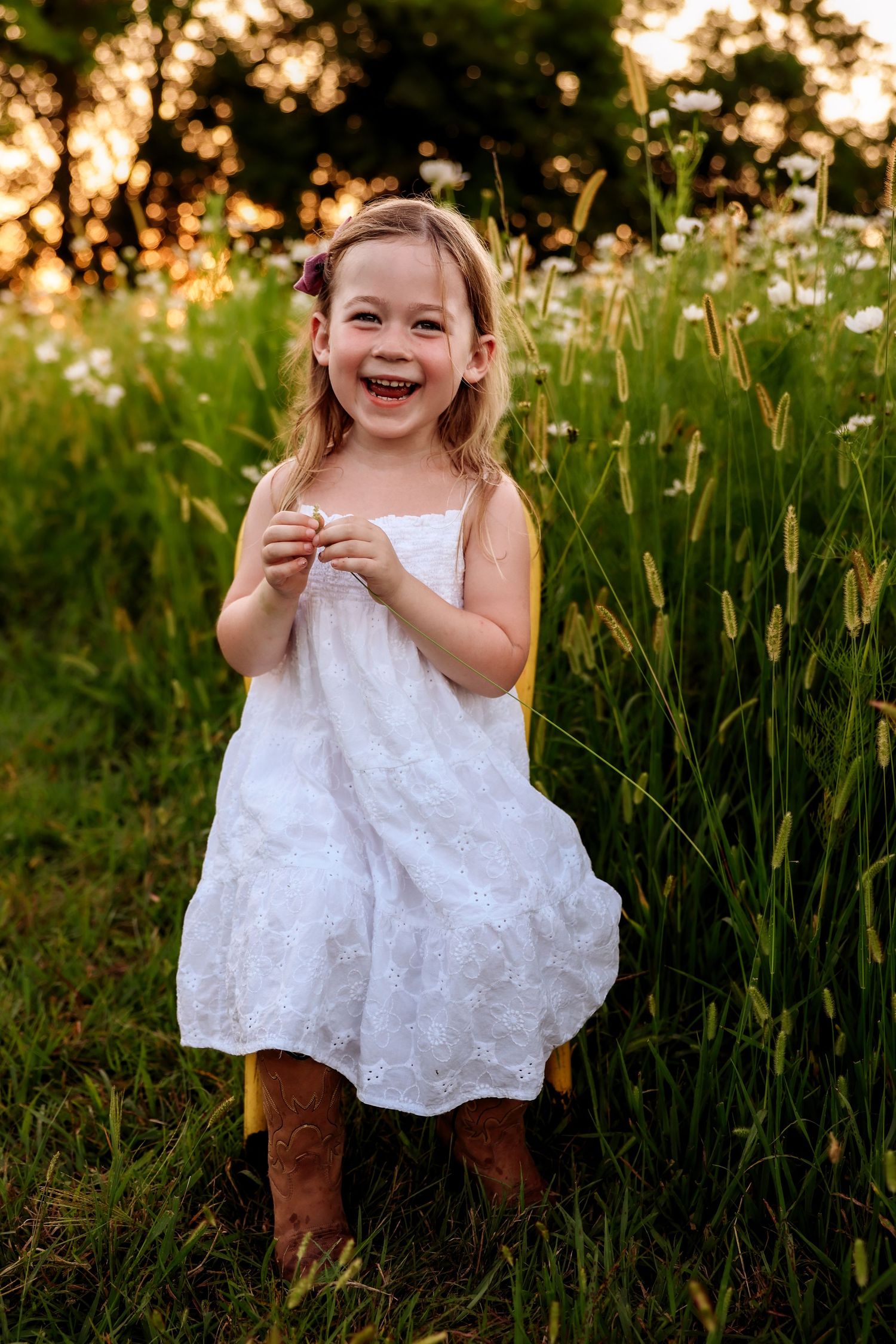 White eyelet dress twirls through tall wildflowers and daisies at sunset.