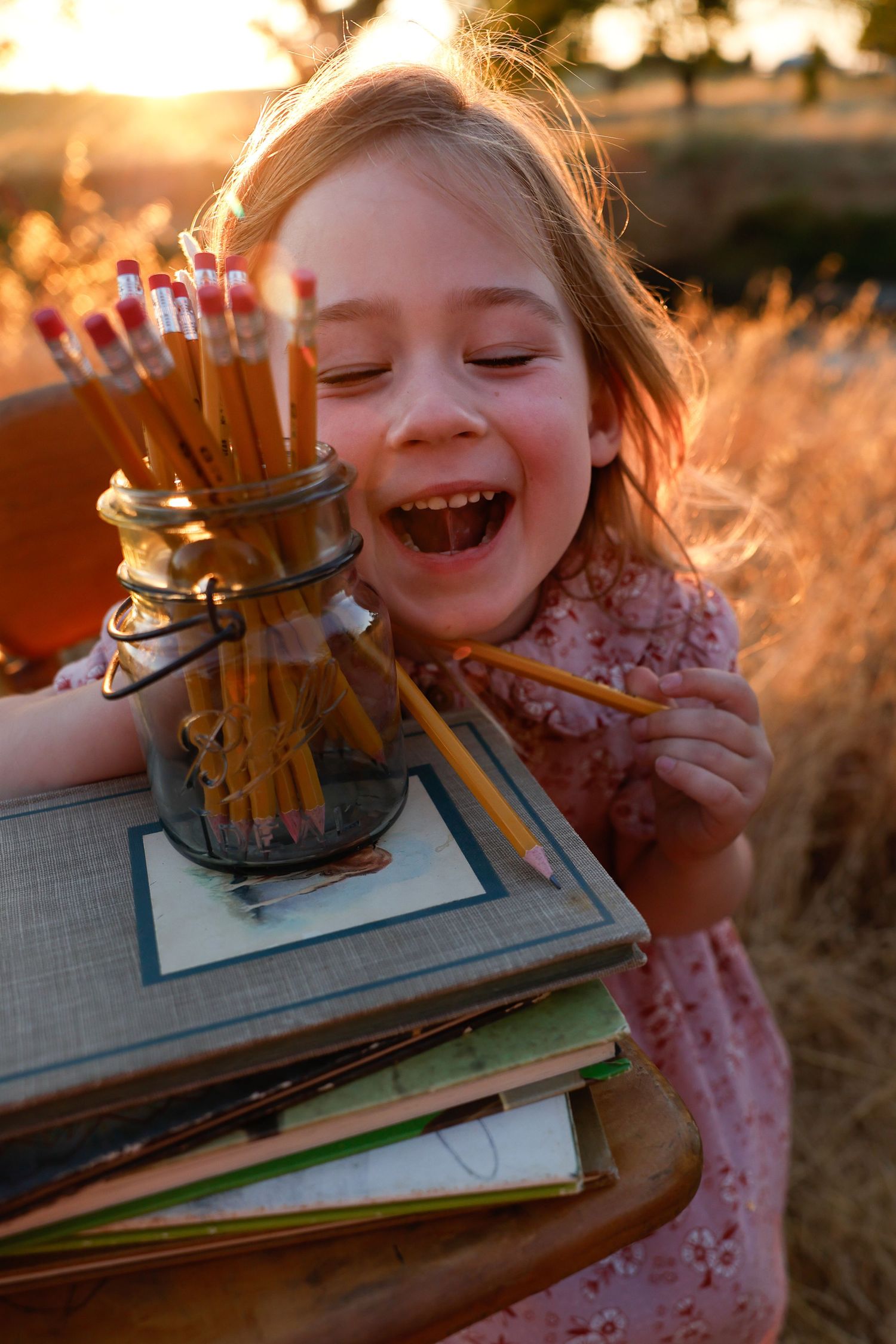 Pure joy radiates in this sunset portrait with vintage books and warm lighting.