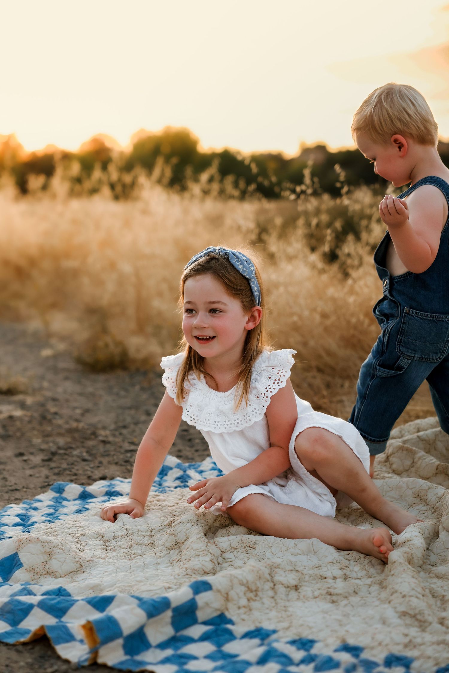 Joyful playtime on a blue checkered blanket during outdoor photoshoot.