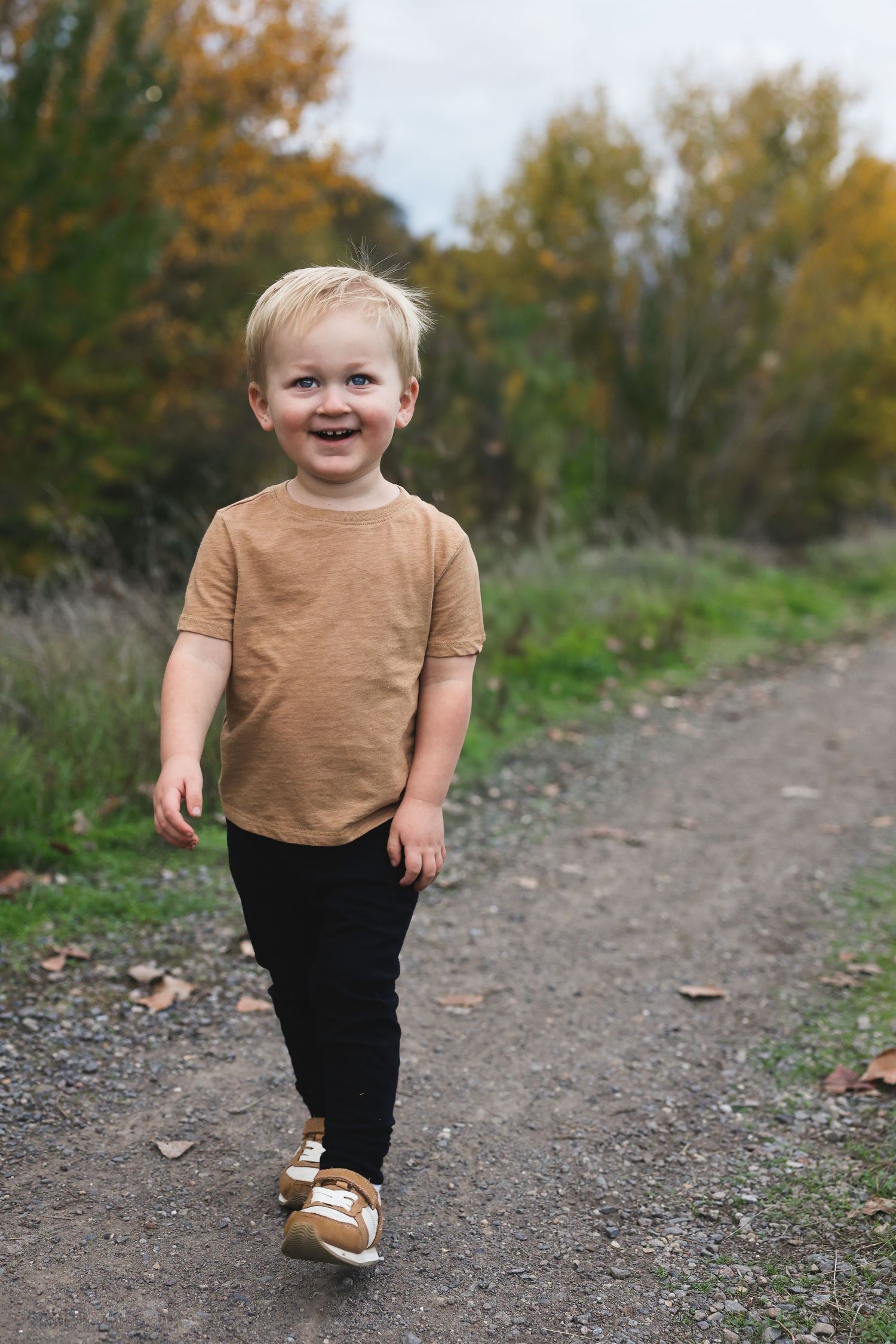 Casual brown shirt and black pants ensemble shown on outdoor walking path.