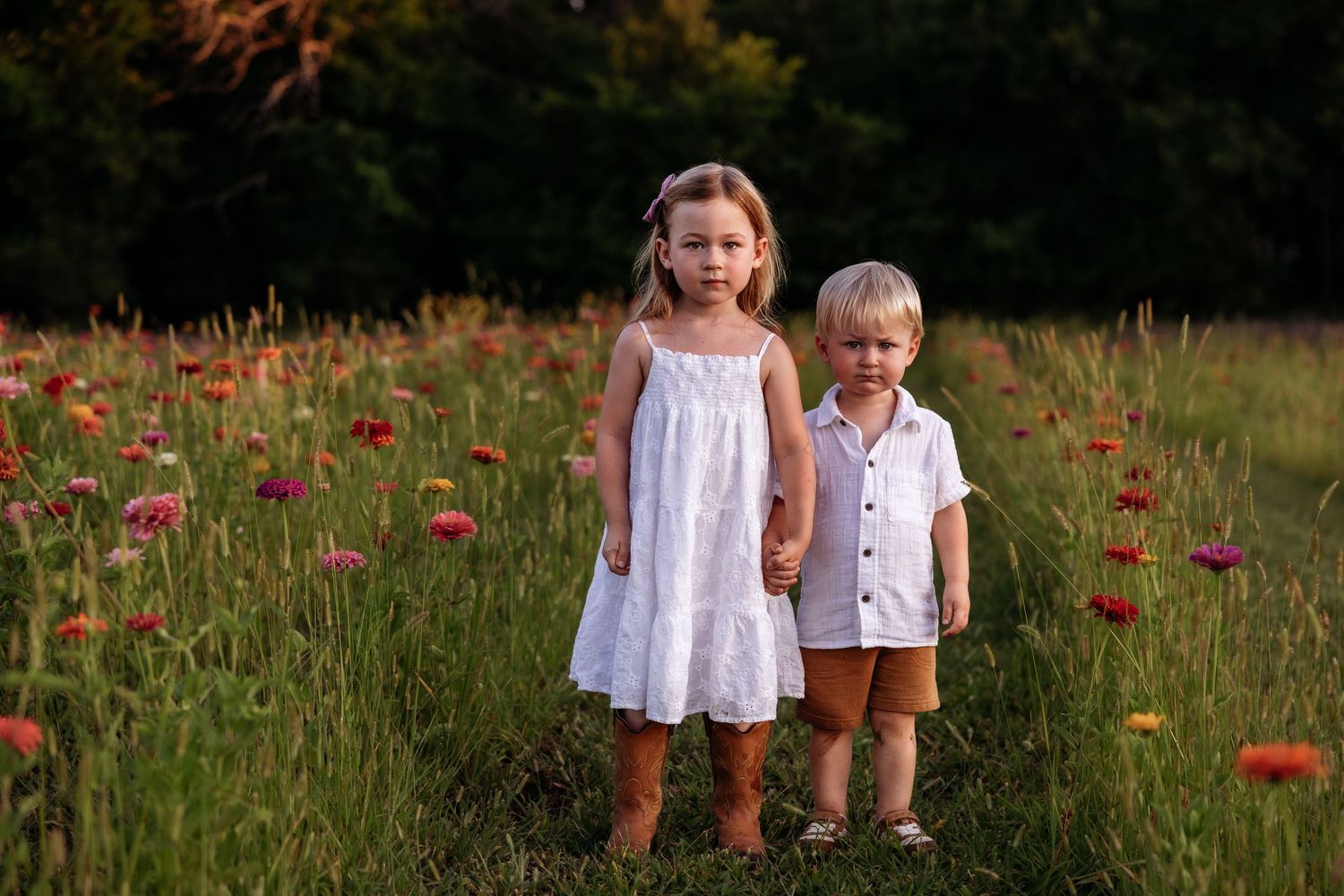 Small kids photographed in wildflower zinnia patch.