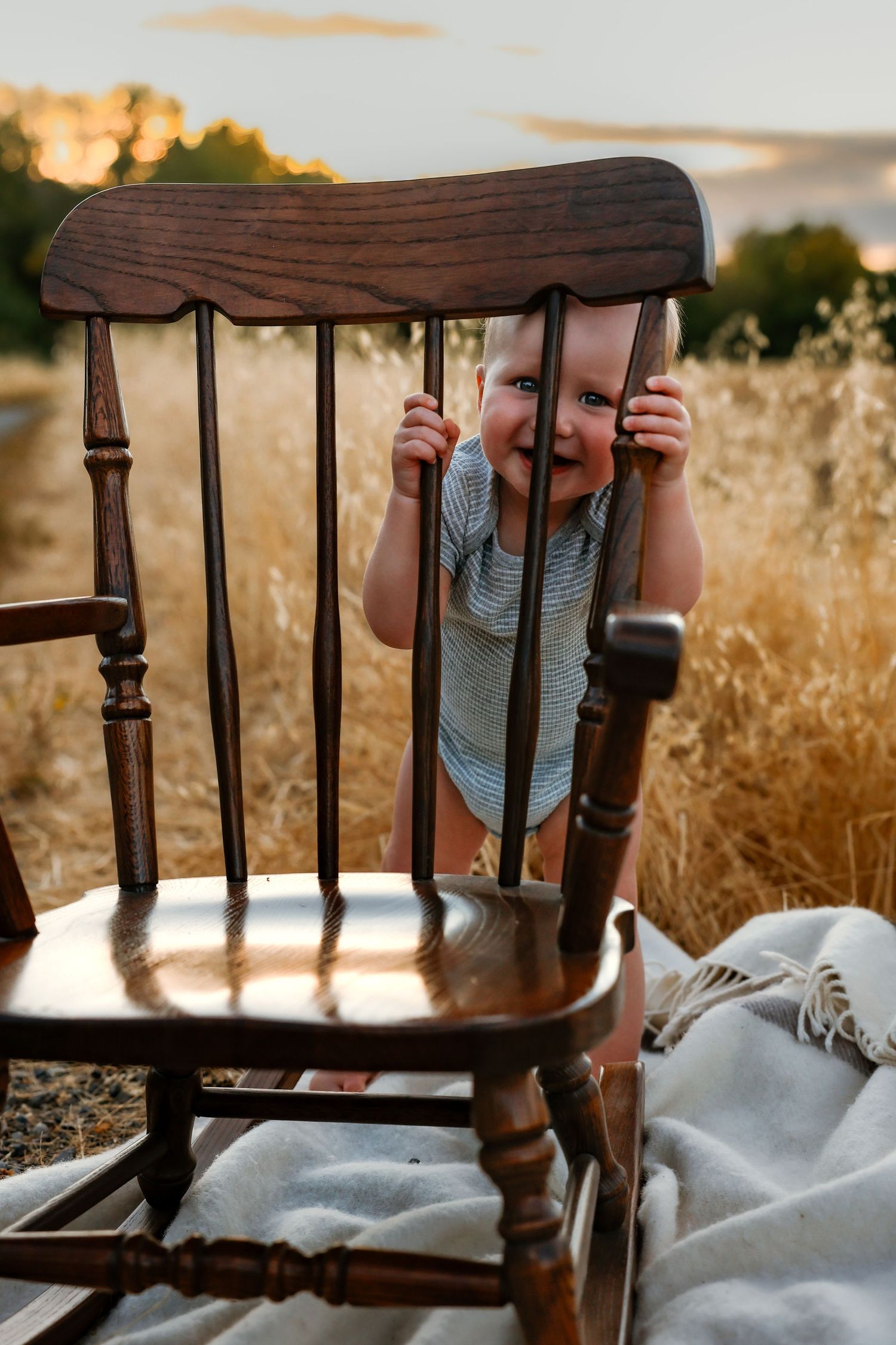 Vintage wooden rocking chair detail against golden sunset background.